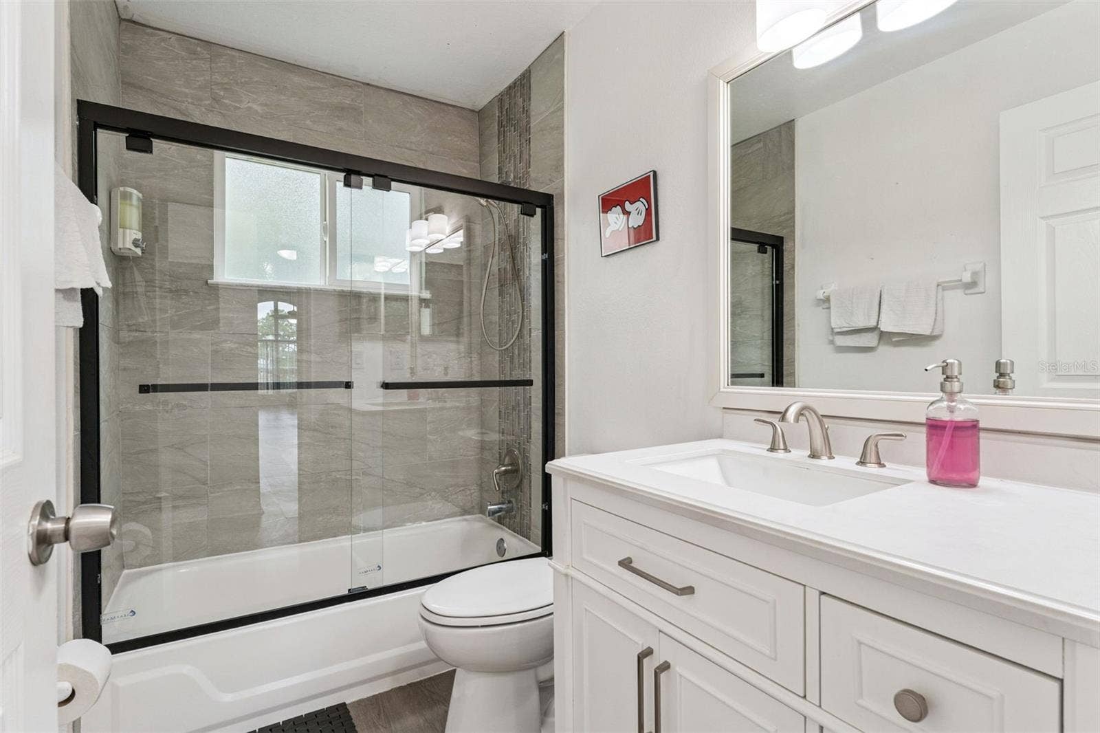 5017 LAGUNA BAY CIRCLE, #100, Kissimmee, FL 34746 Full Bathroom & Shower: Updated full bathroom complete with a white vanity, modern matte black sliding glass shower doors, and sleek tile surround.