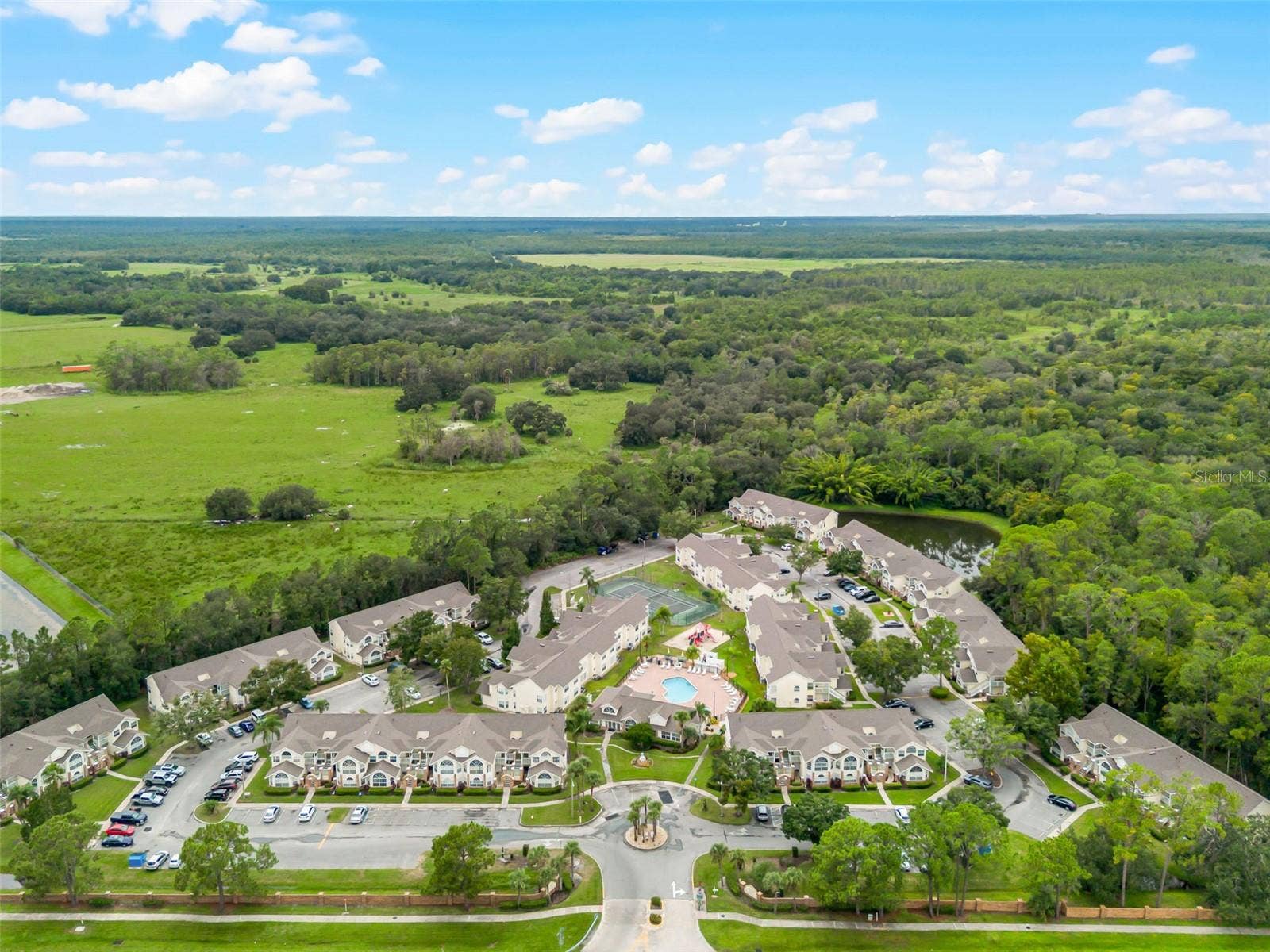 5017 LAGUNA BAY CIRCLE, #100, Kissimmee, FL 34746 Wide Regional Aerial View: Panoramic high-altitude aerial perspective displaying the entire community layout, lush conservation borders, retention pond, and scenic green horizon.