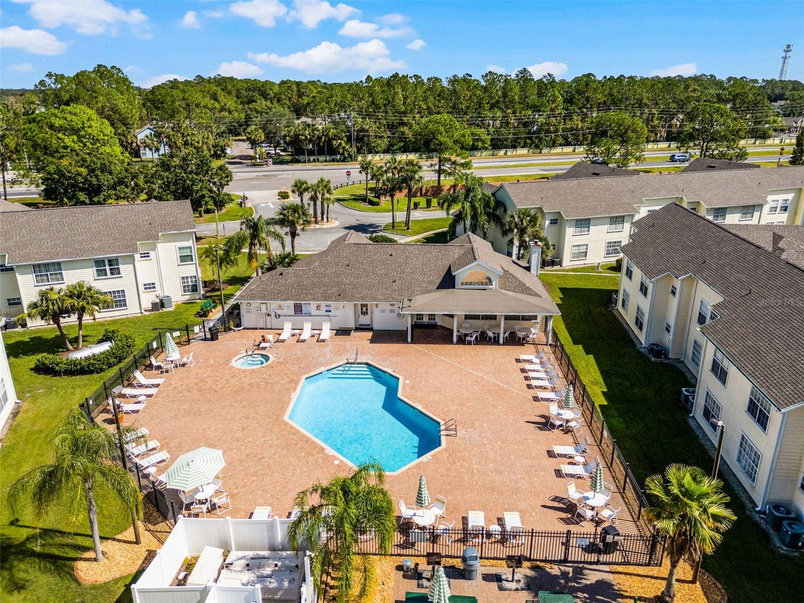 5017 LAGUNA BAY CIRCLE, #100, Kissimmee, FL 34746 Pool & Spa Complex: Overhead aerial capture of the sparkling resort pool, heated spa, paved lounge deck, covered clubhouse patio, and tropical landscaping.
