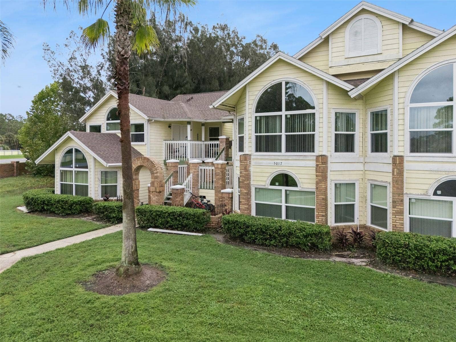 5017 LAGUNA BAY CIRCLE, #100, Kissimmee, FL 34746 Exterior Elevation: Dynamic exterior angle displaying distinctive window styling, palm trees, and covered staircase entryways.