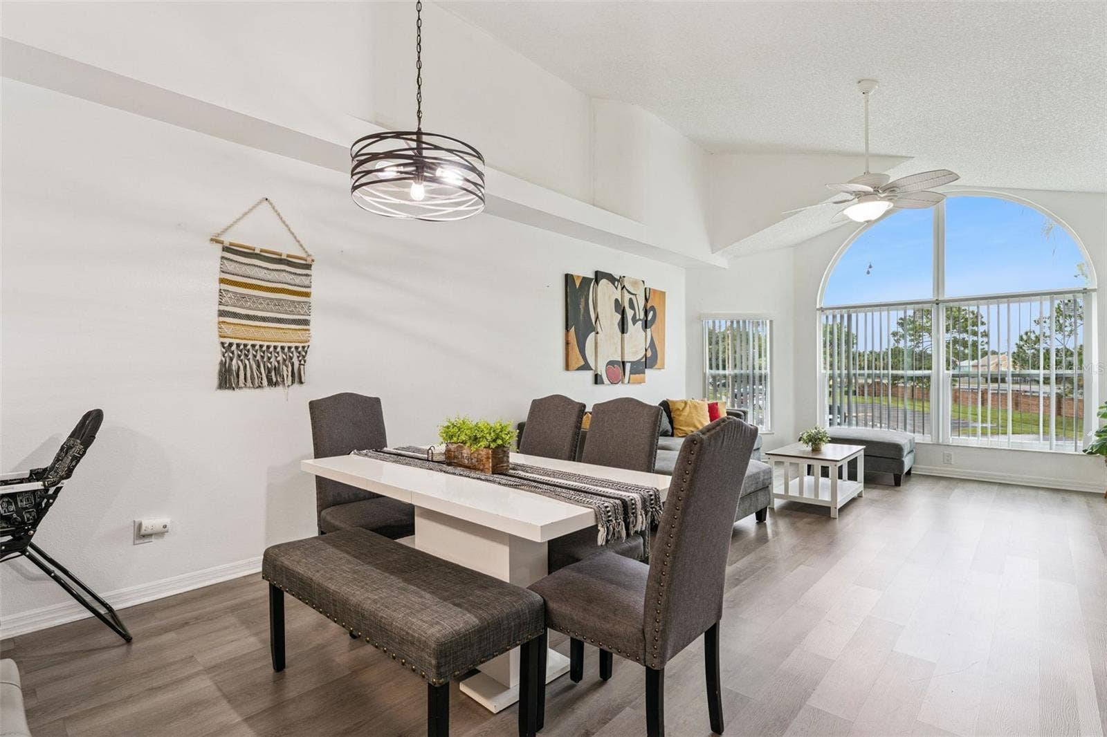 5017 LAGUNA BAY CIRCLE, #100, Kissimmee, FL 34746 Dining Area: Dining space featuring an overhead modern chandelier fixture, dining table with bench seating, and smooth flow into the main living room.