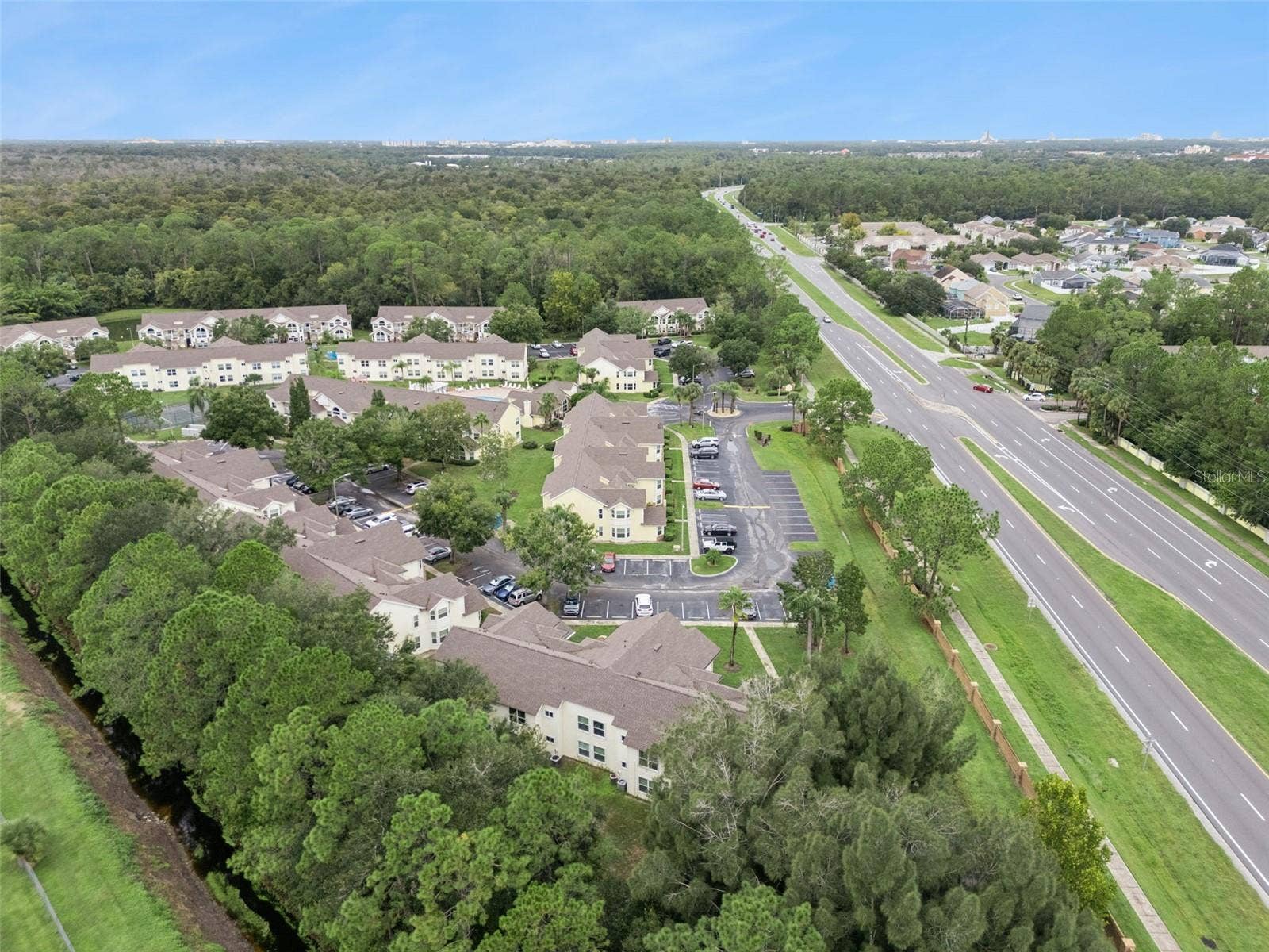 5017 LAGUNA BAY CIRCLE, #100, Kissimmee, FL 34746 Panoramic Community View: Panoramic drone view capturing the expansive residential complex layout, mature tree canopy, water features, and regional connectivity.