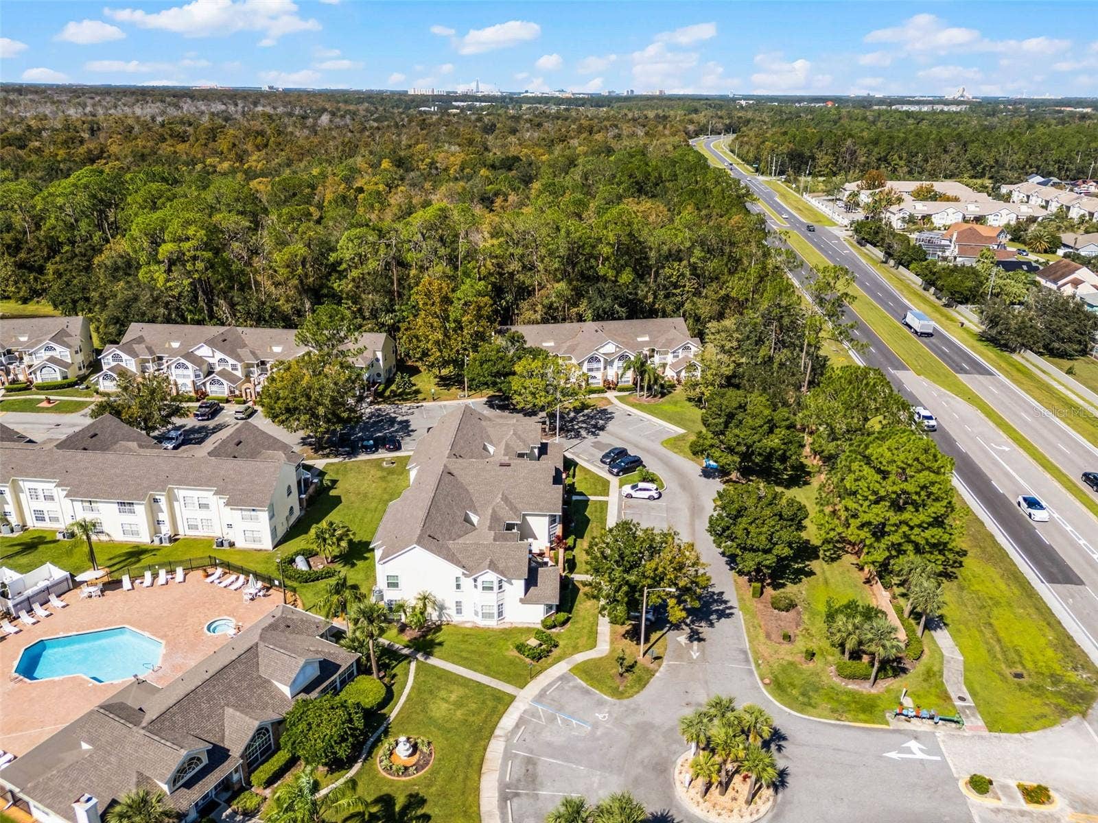5017 LAGUNA BAY CIRCLE, #100, Kissimmee, FL 34746 Community Entrance & Highway Proximity: Aerial overview featuring the main community drive, entrance roundabout, amenity center, and adjacent major roadway for easy commuting.