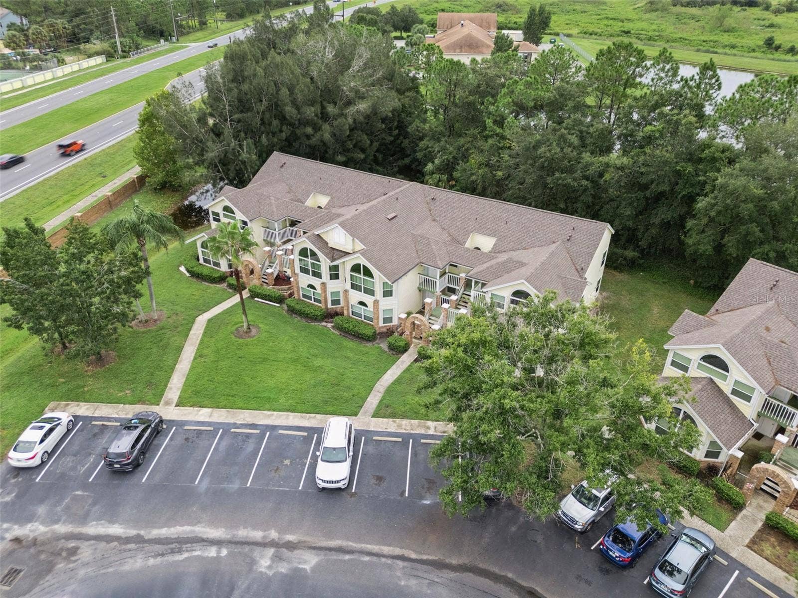 5017 LAGUNA BAY CIRCLE, #100, Kissimmee, FL 34746 Front Aerial & Parking: High-angle front aerial view of the building, highlighting convenient front parking stalls, paved walkways, and lush surrounding greenery.