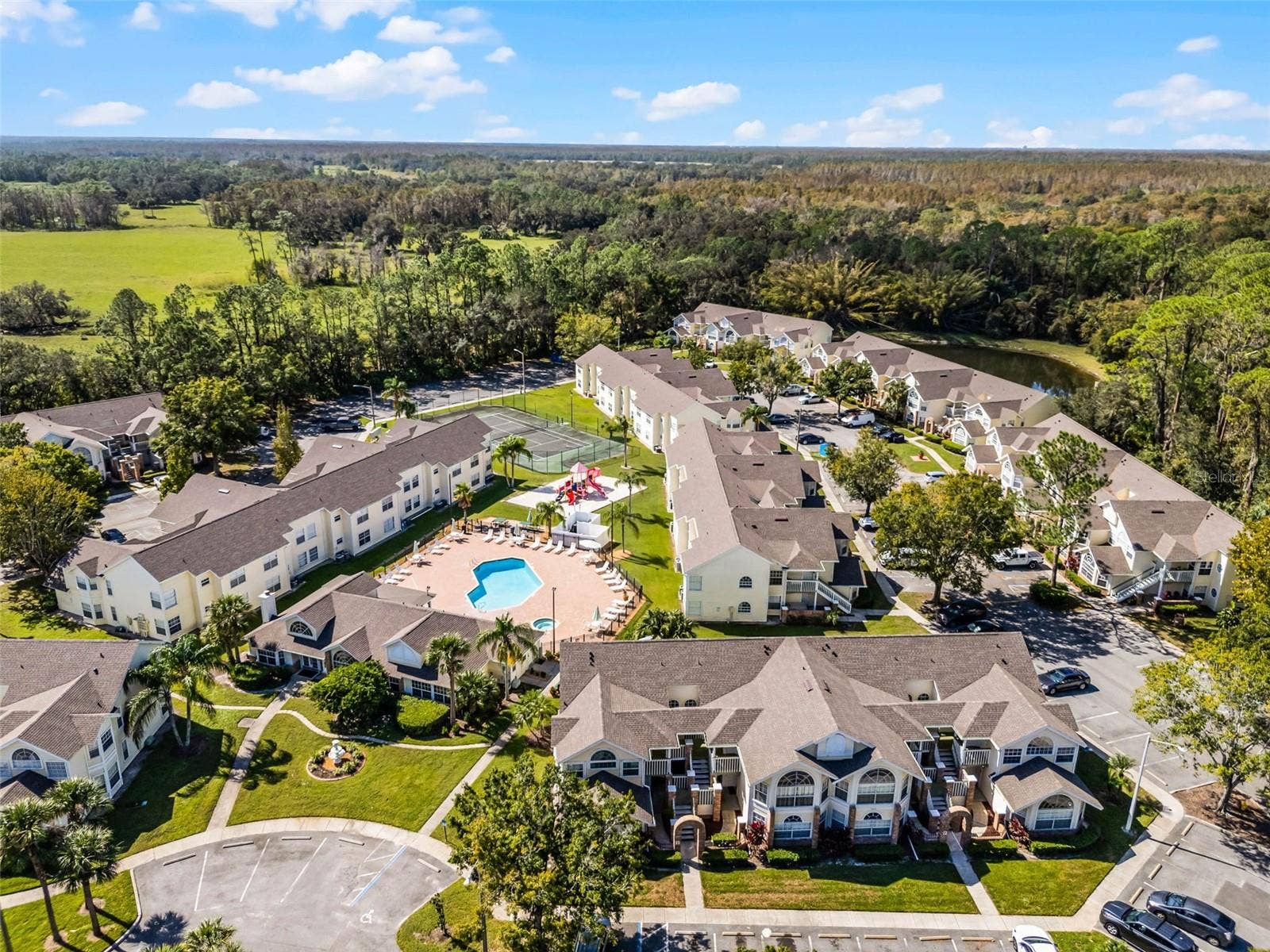 5017 LAGUNA BAY CIRCLE, #100, Kissimmee, FL 34746 Community Grounds Aerial: High-angle drone perspective emphasizing the expansive community layout, amenity center, and tree-lined perimeter.