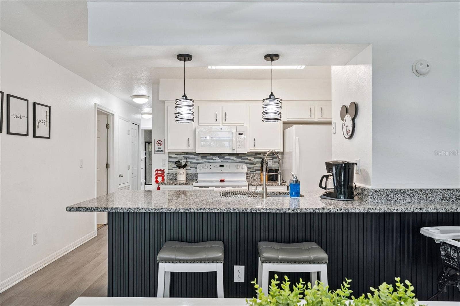 5017 LAGUNA BAY CIRCLE, #100, Kissimmee, FL 34746 Breakfast Bar Seating: Custom vertical-slat accent breakfast bar with granite countertop overhang, stool seating, and updated pendant light fixtures.