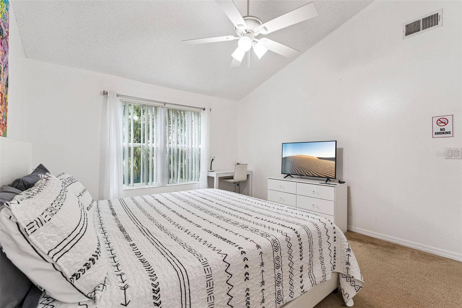 5017 LAGUNA BAY CIRCLE, #100, Kissimmee, FL 34746 Primary Bedroom: Bright primary bedroom featuring vaulted ceilings, a ceiling fan, plush carpeting, dedicated work/desk nook, and large window for natural light.