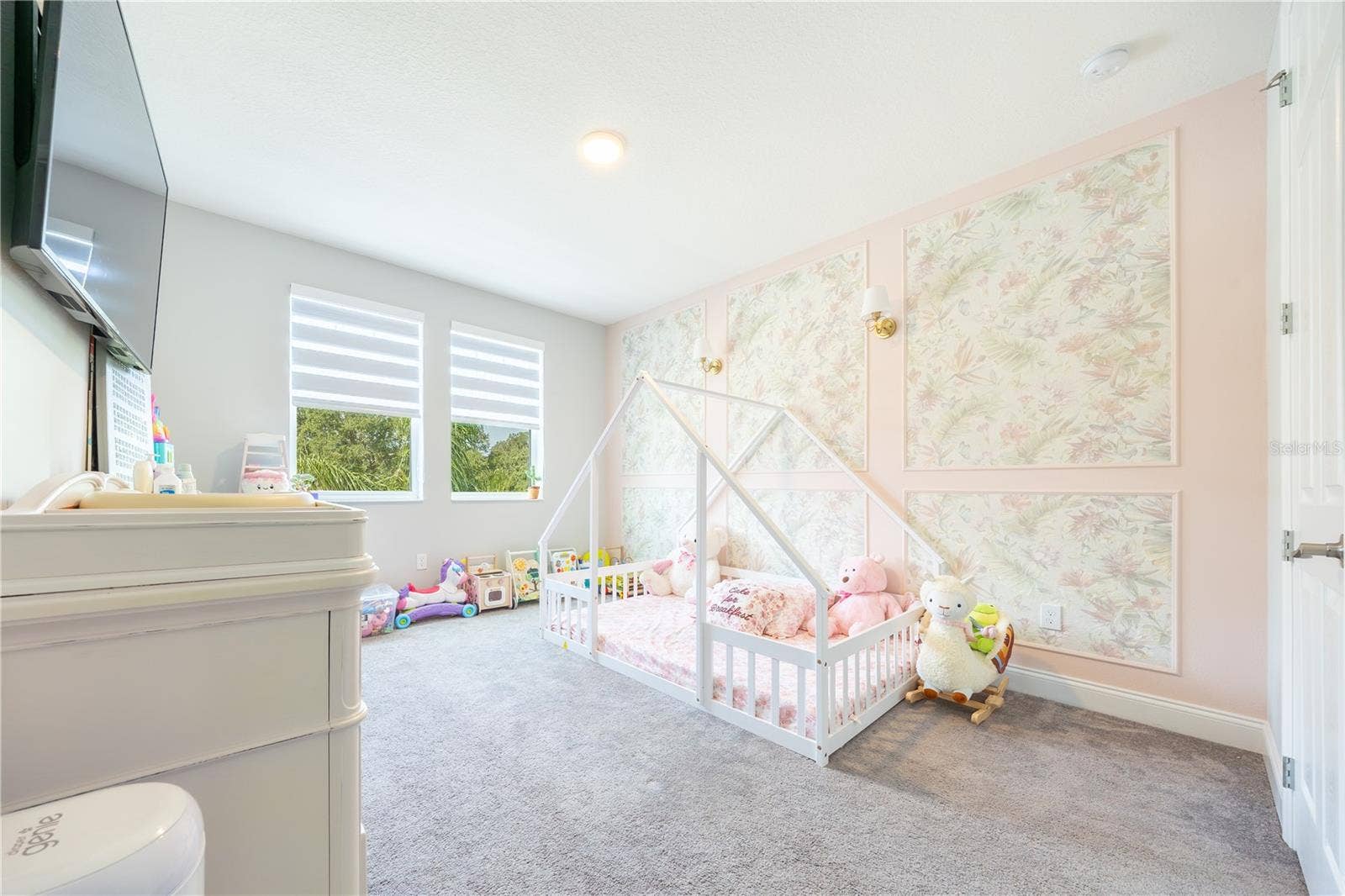 1316 SOUTHERN SUN DRIVE, Oakland, FL 34787 Charming bedroom with a floral accent wall, decorative sconces, and windows with lake views.