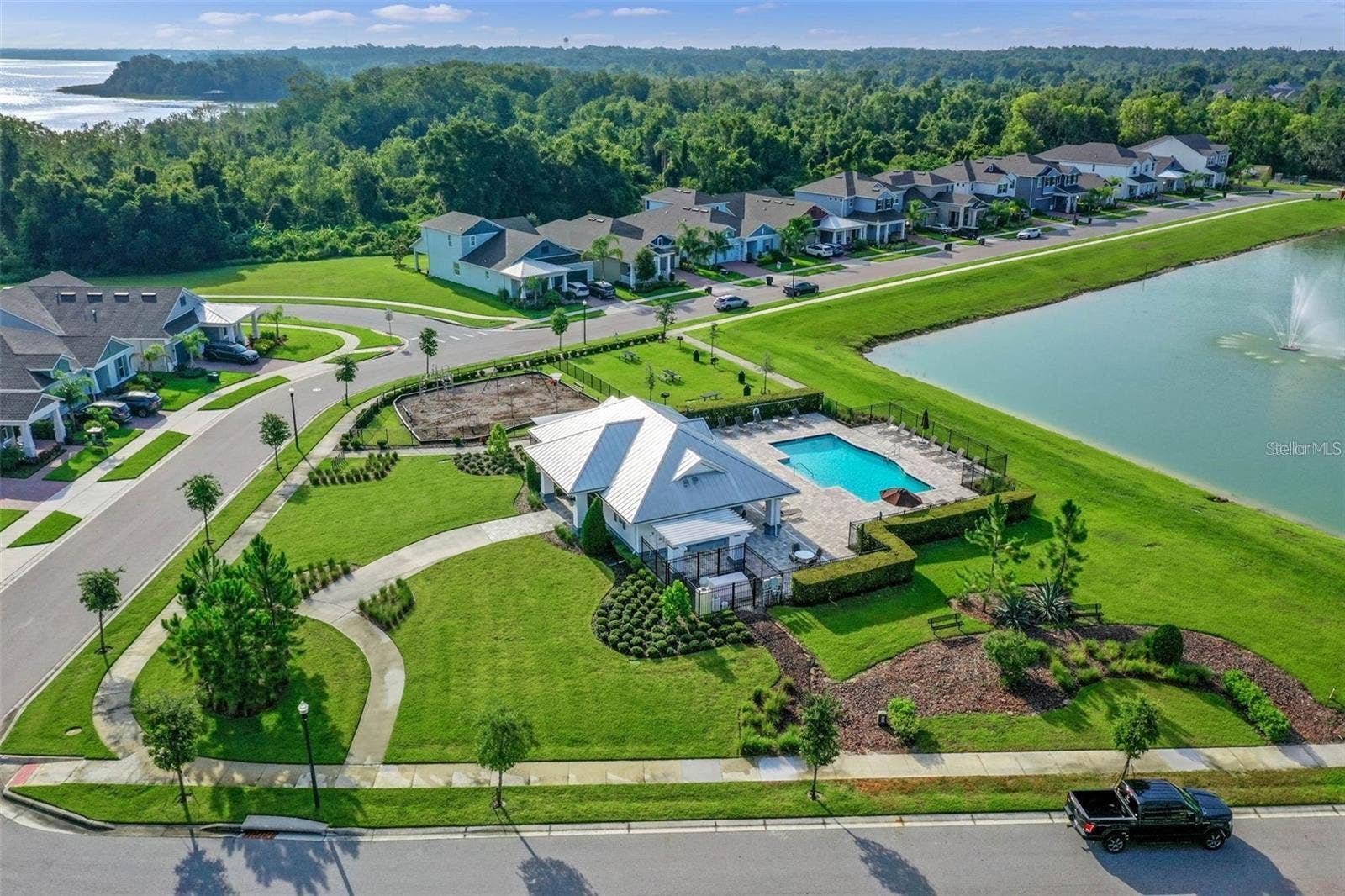 1316 SOUTHERN SUN DRIVE, Oakland, FL 34787 Aerial view of the community pool, playground, and landscaped walking paths beside a scenic pond.