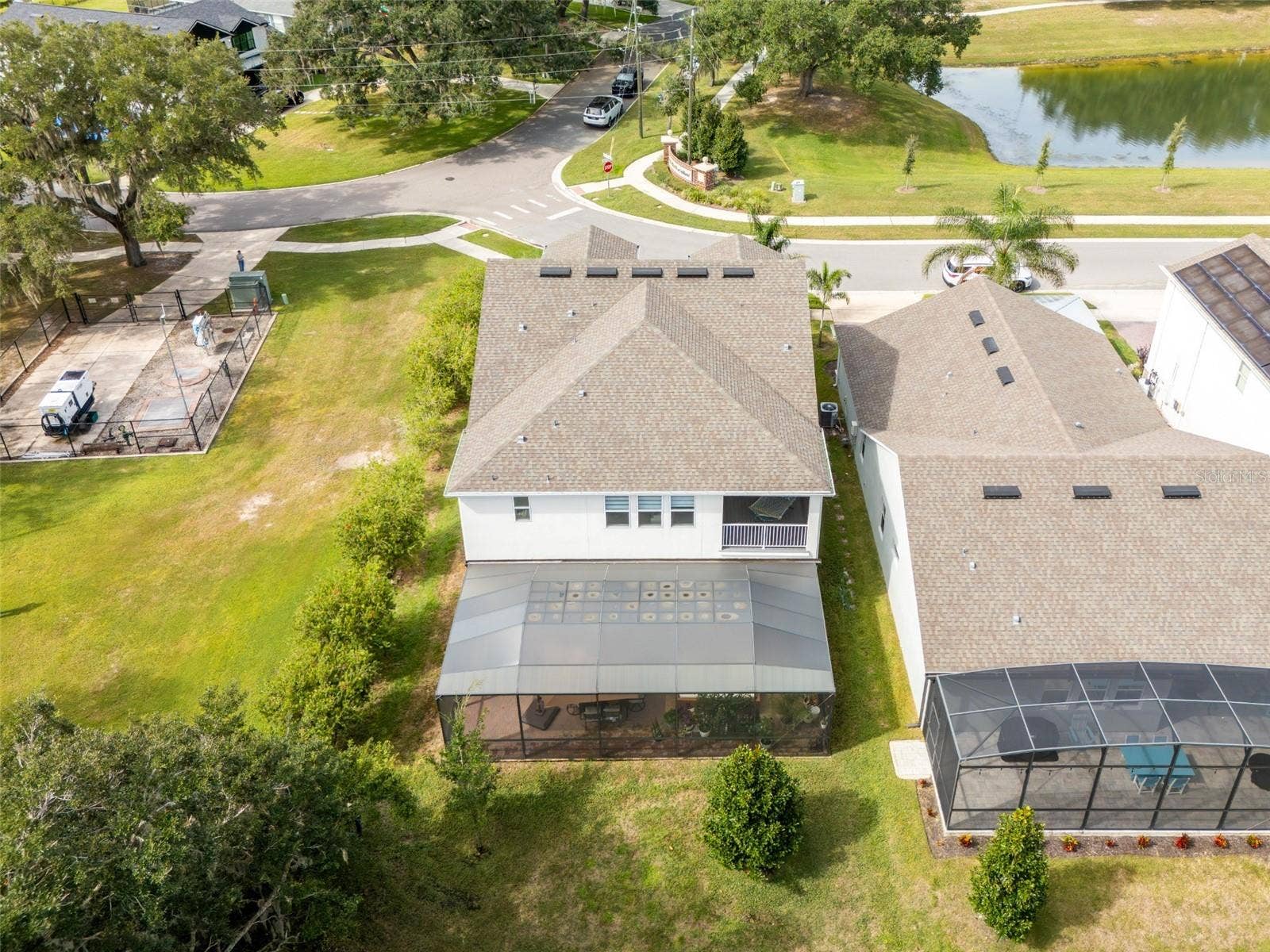 1316 SOUTHERN SUN DRIVE, Oakland, FL 34787 Rear aerial view showcasing an expansive screened patio, covered upstairs balcony, and wooded surroundings.