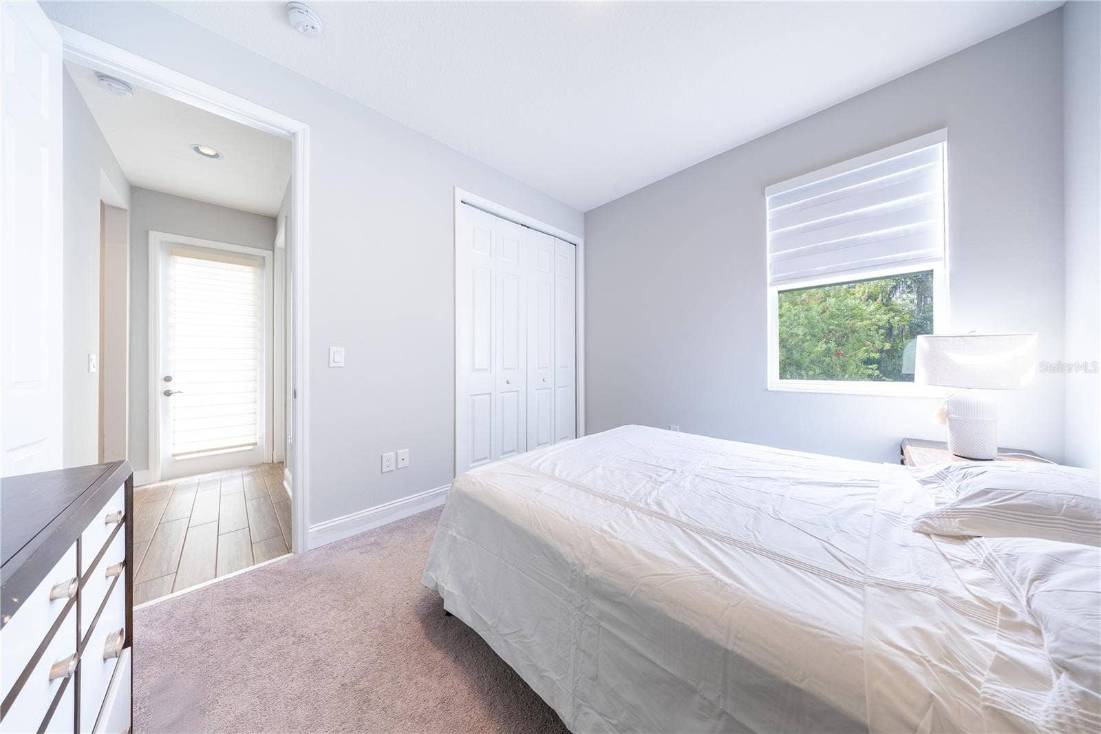 1316 SOUTHERN SUN DRIVE, Oakland, FL 34787 Bedroom with soft neutral tones, carpet flooring, a closet with folding doors, and a window overlooking greenery.