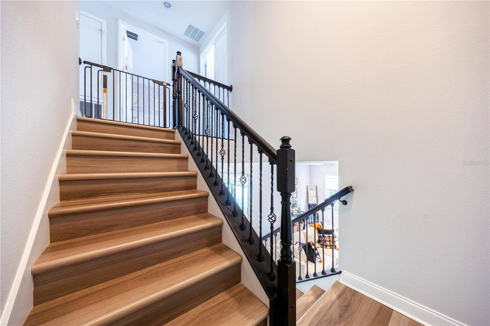 1316 SOUTHERN SUN DRIVE, Oakland, FL 34787 Elegant staircase with warm wood-look finishes and decorative metal railings leading to the upper level.