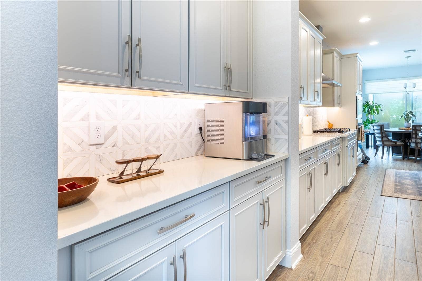 1316 SOUTHERN SUN DRIVE, Oakland, FL 34787 Stylish serving area with white cabinetry, geometric tile backsplash, and under-cabinet lighting.