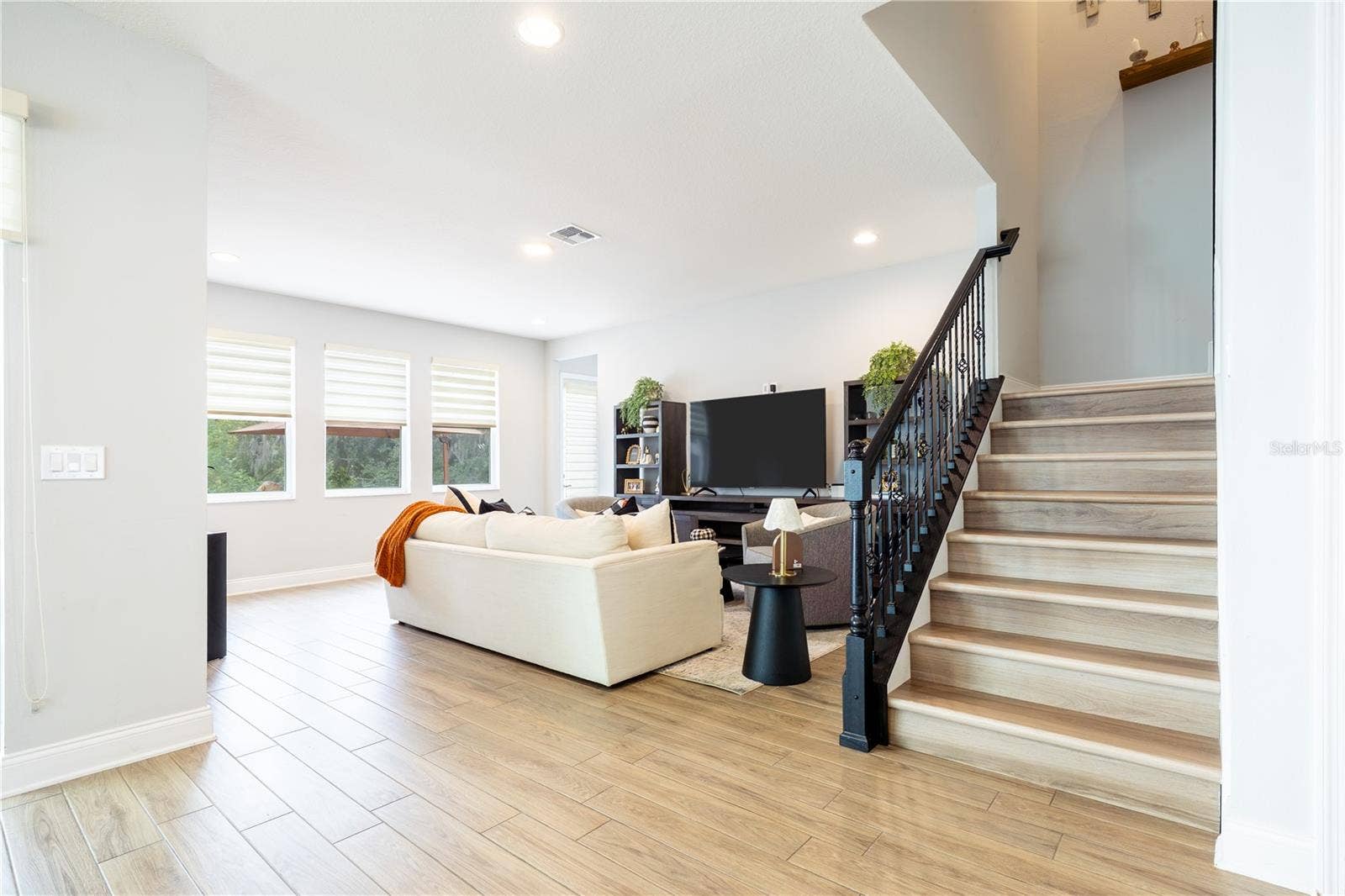 1316 SOUTHERN SUN DRIVE, Oakland, FL 34787 Elegant staircase with decorative metal railings beside an inviting living room with garden views.