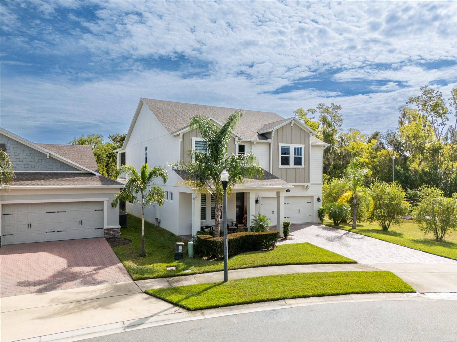 1316 SOUTHERN SUN DRIVE, Oakland, FL 34787 Elevated front view showcasing elegant curb appeal, tropical landscaping, and a two-car garage.