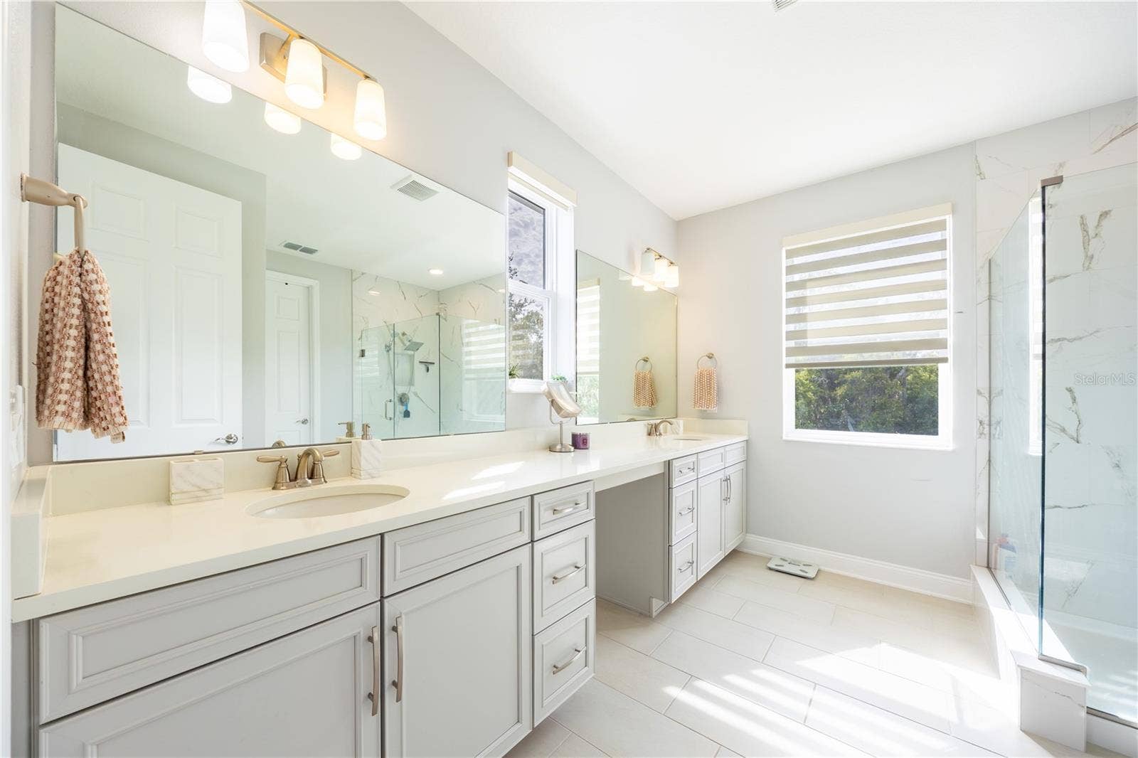 1316 SOUTHERN SUN DRIVE, Oakland, FL 34787 Elegant bathroom with a dual-sink vanity, dressing area, and glass-enclosed shower.