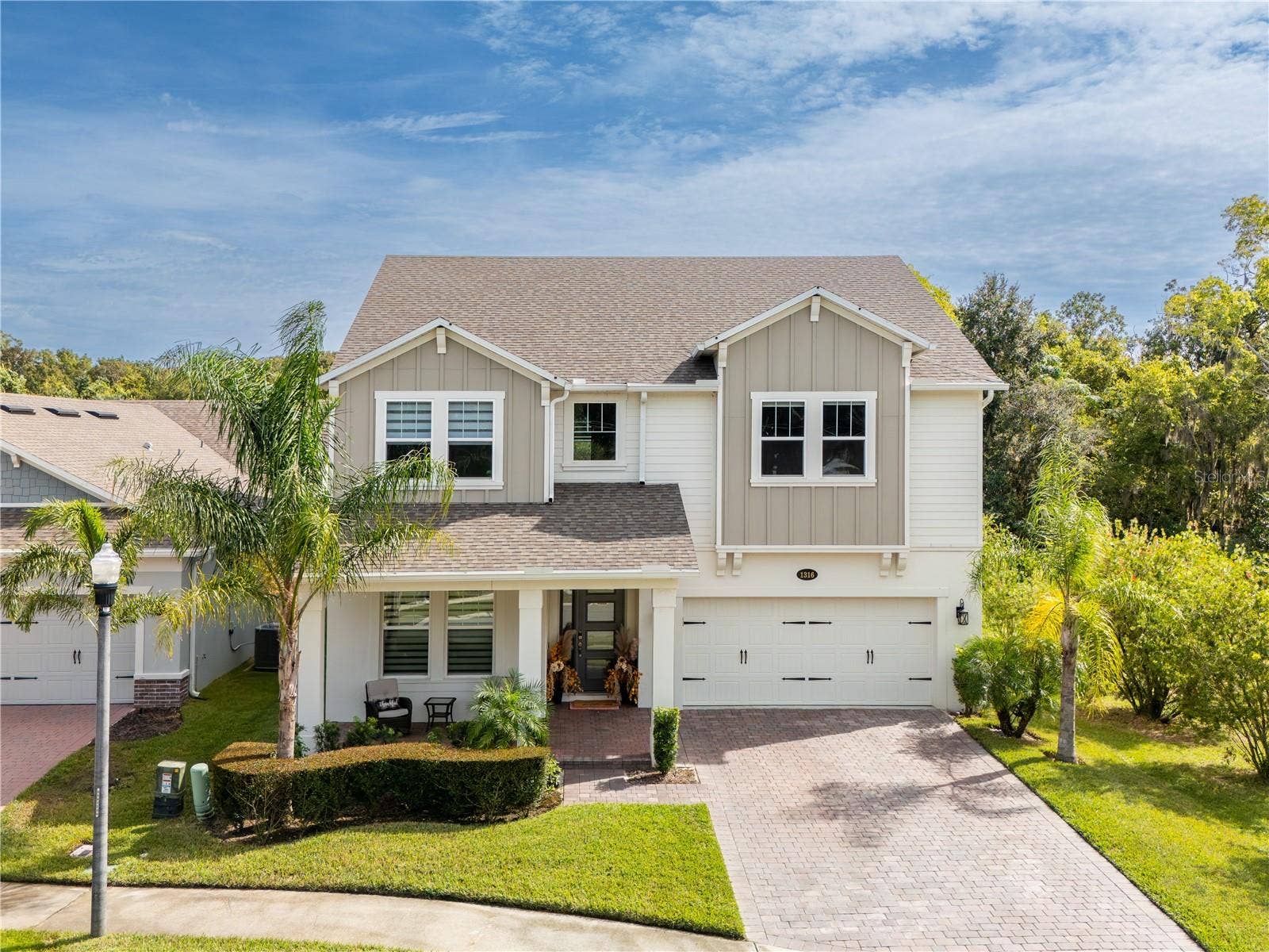 1316 SOUTHERN SUN DRIVE, Oakland, FL 34787 Elegant two-story home with a covered front porch, paver driveway, and tropical landscaping.
