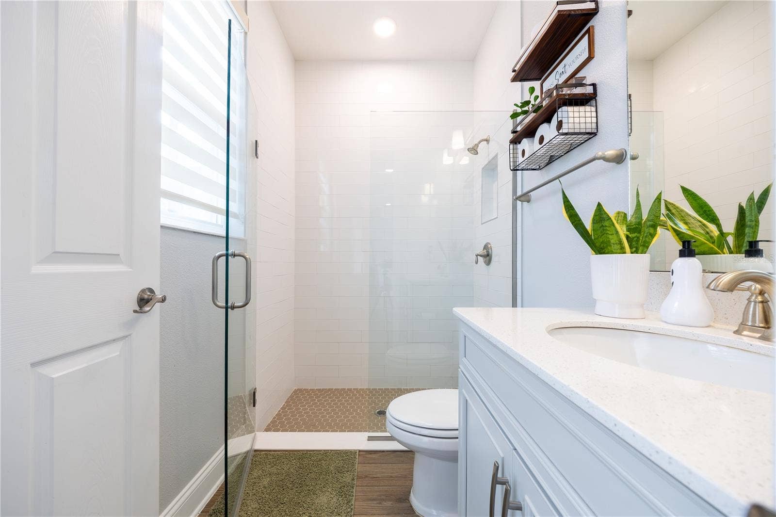 1316 SOUTHERN SUN DRIVE, Oakland, FL 34787 Bright bathroom featuring a frameless glass shower, white tile walls, mosaic shower floor, and a spacious vanity countertop.