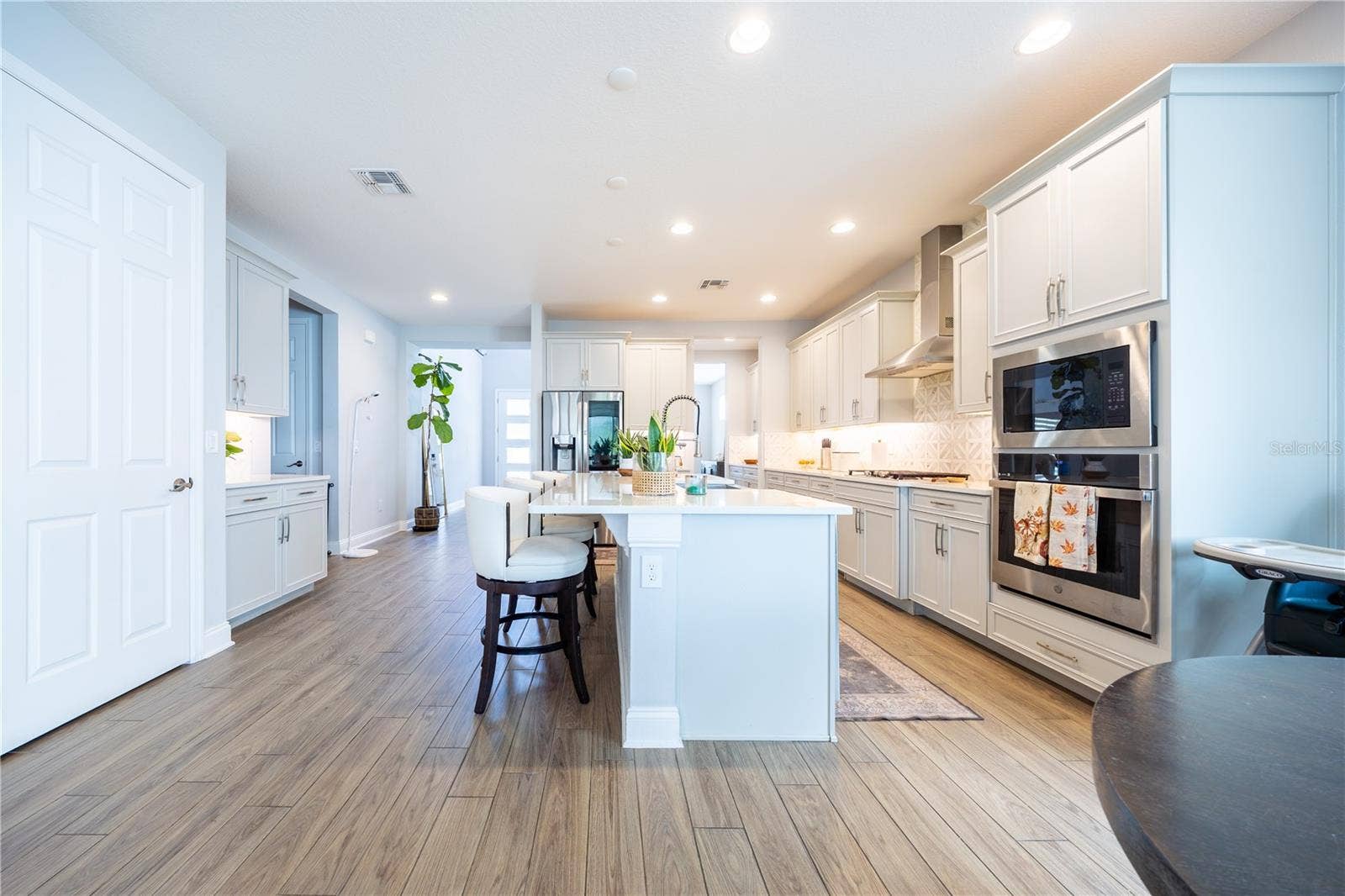 1316 SOUTHERN SUN DRIVE, Oakland, FL 34787 Elegant kitchen with white cabinetry, a spacious island with seating, and stainless steel appliances.