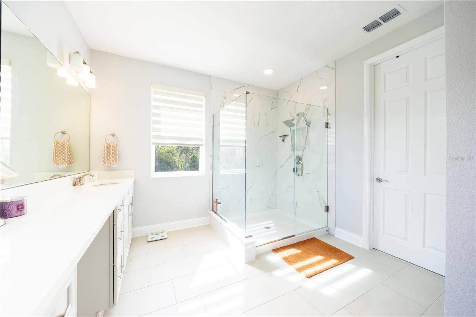1316 SOUTHERN SUN DRIVE, Oakland, FL 34787 Refined primary bathroom with a frameless glass shower and marble-look tile finishes.