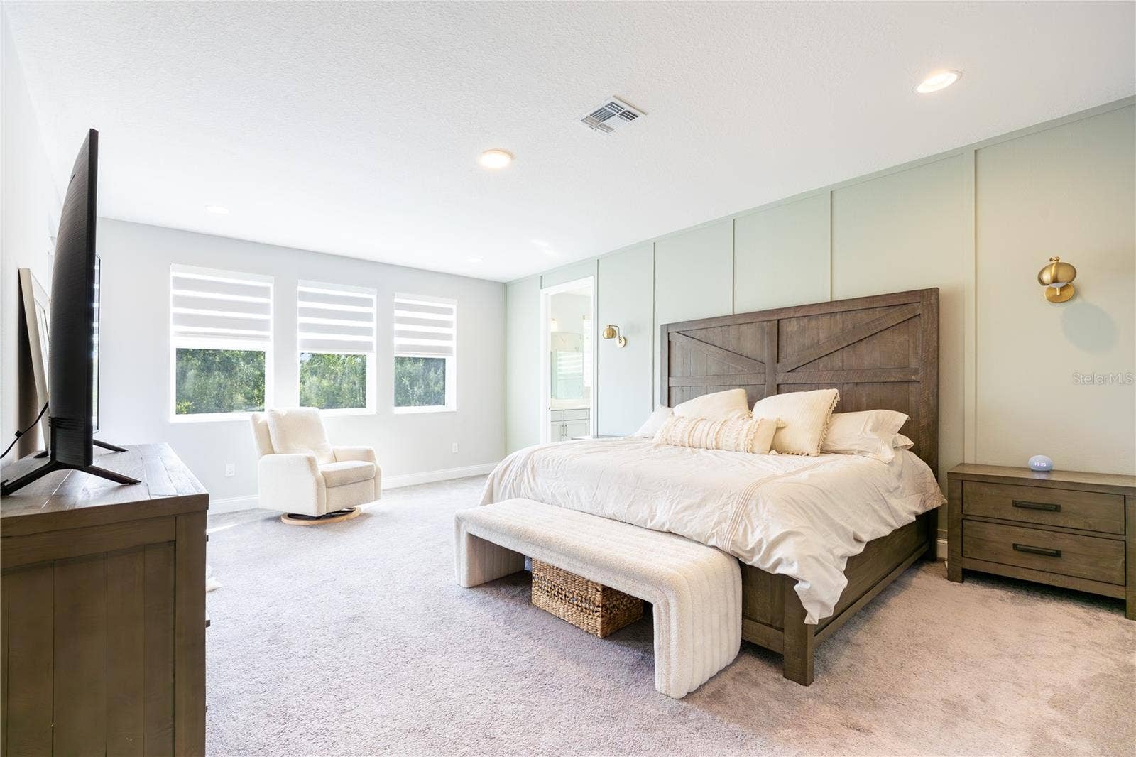 1316 SOUTHERN SUN DRIVE, Oakland, FL 34787 Spacious primary bedroom with an elegant accent wall, sitting area, and porch access with views of a conservation area.