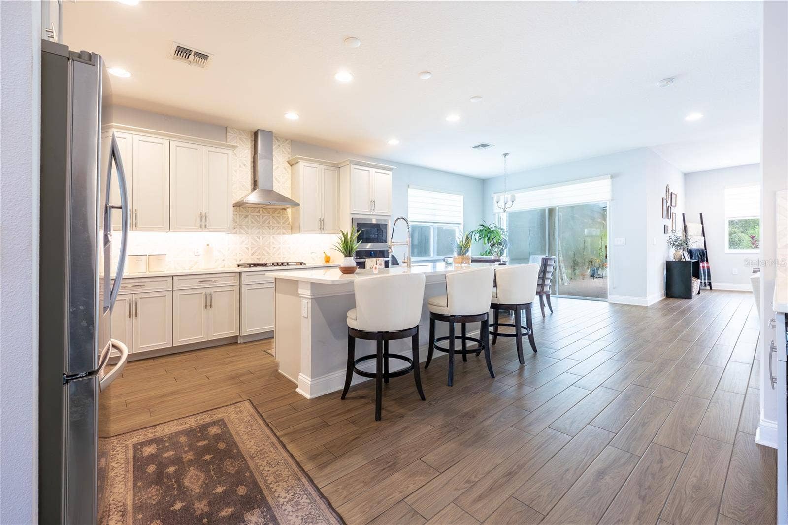 1316 SOUTHERN SUN DRIVE, Oakland, FL 34787 Open-concept kitchen with a generous island, stainless steel range hood, and easy access to the covered patio.