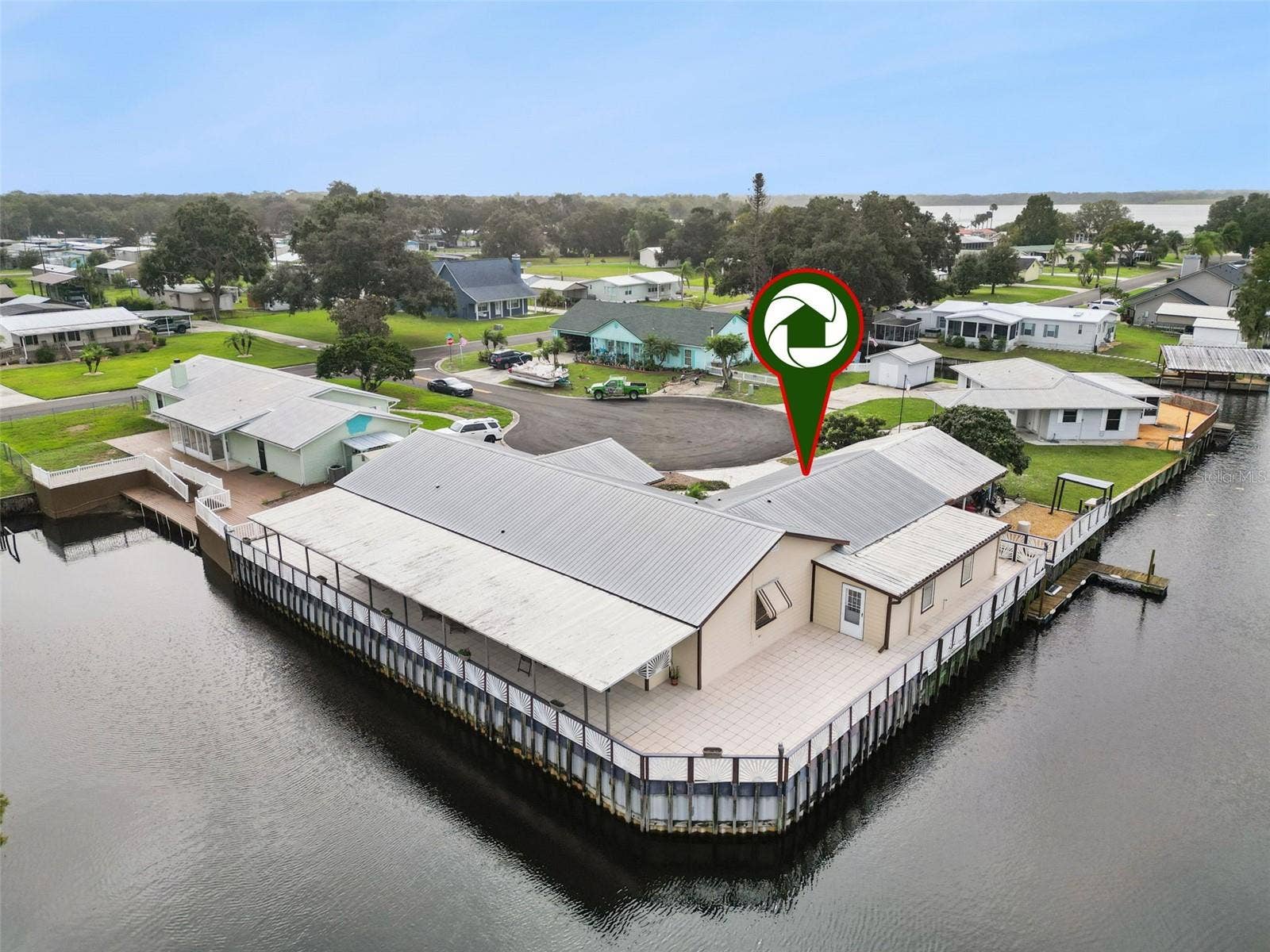 Aerial Rear Deck Pin: High-angle drone perspective featuring a property location pin identifying the home's premier position on the canal point
