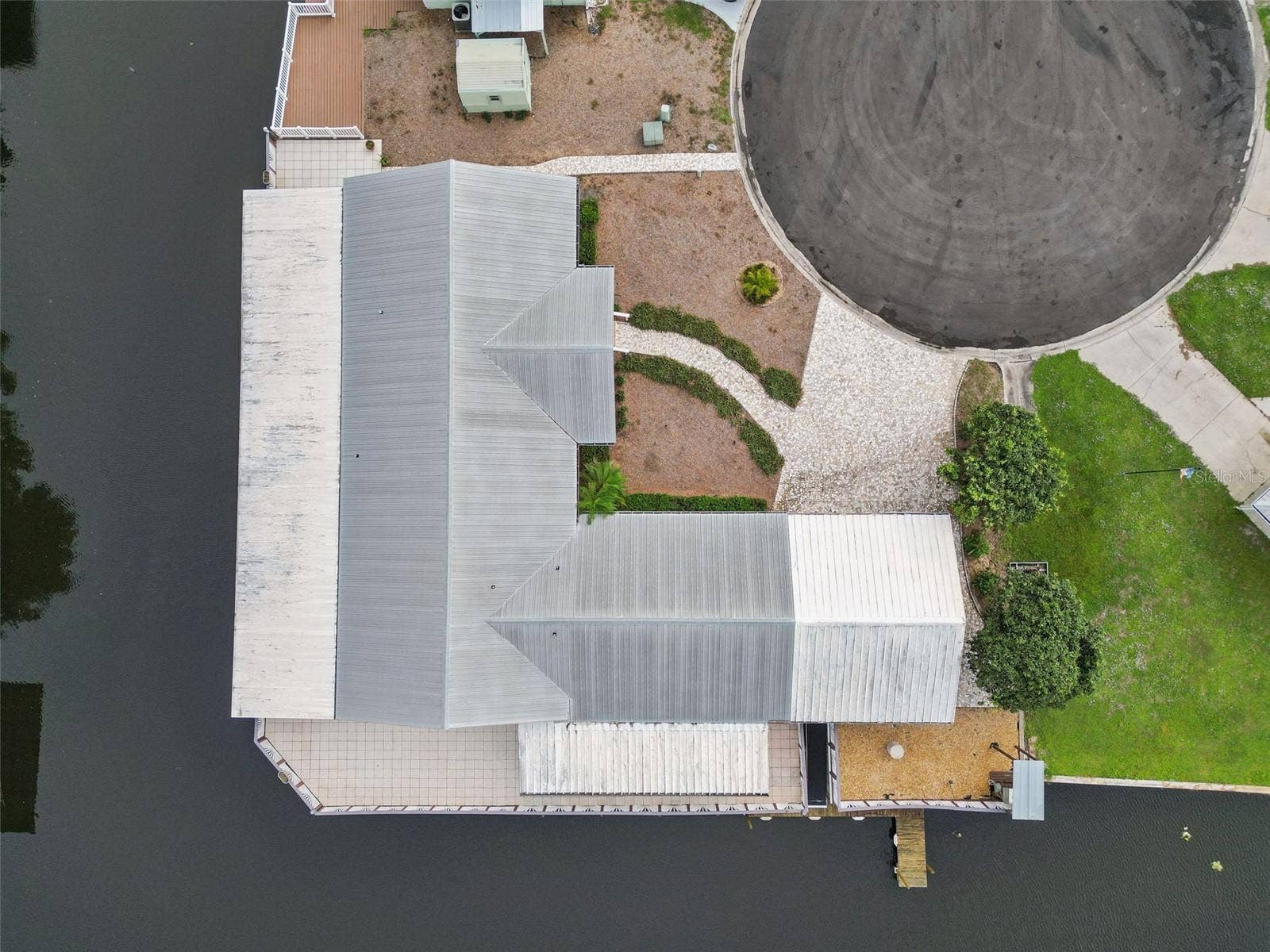 Aerial Top-Down View: Overhead drone shot highlighting the property layout, metal roof, cul-de-sac positioning, and canal wrap-around.