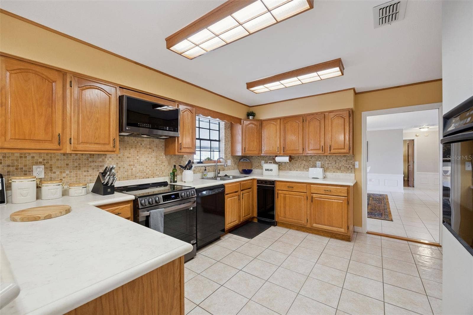 Kitchen Overview: Full kitchen perspective detailing abundant cabinet storage, counter workspace, mosaic tile backsplash, and built-in microwave unit.