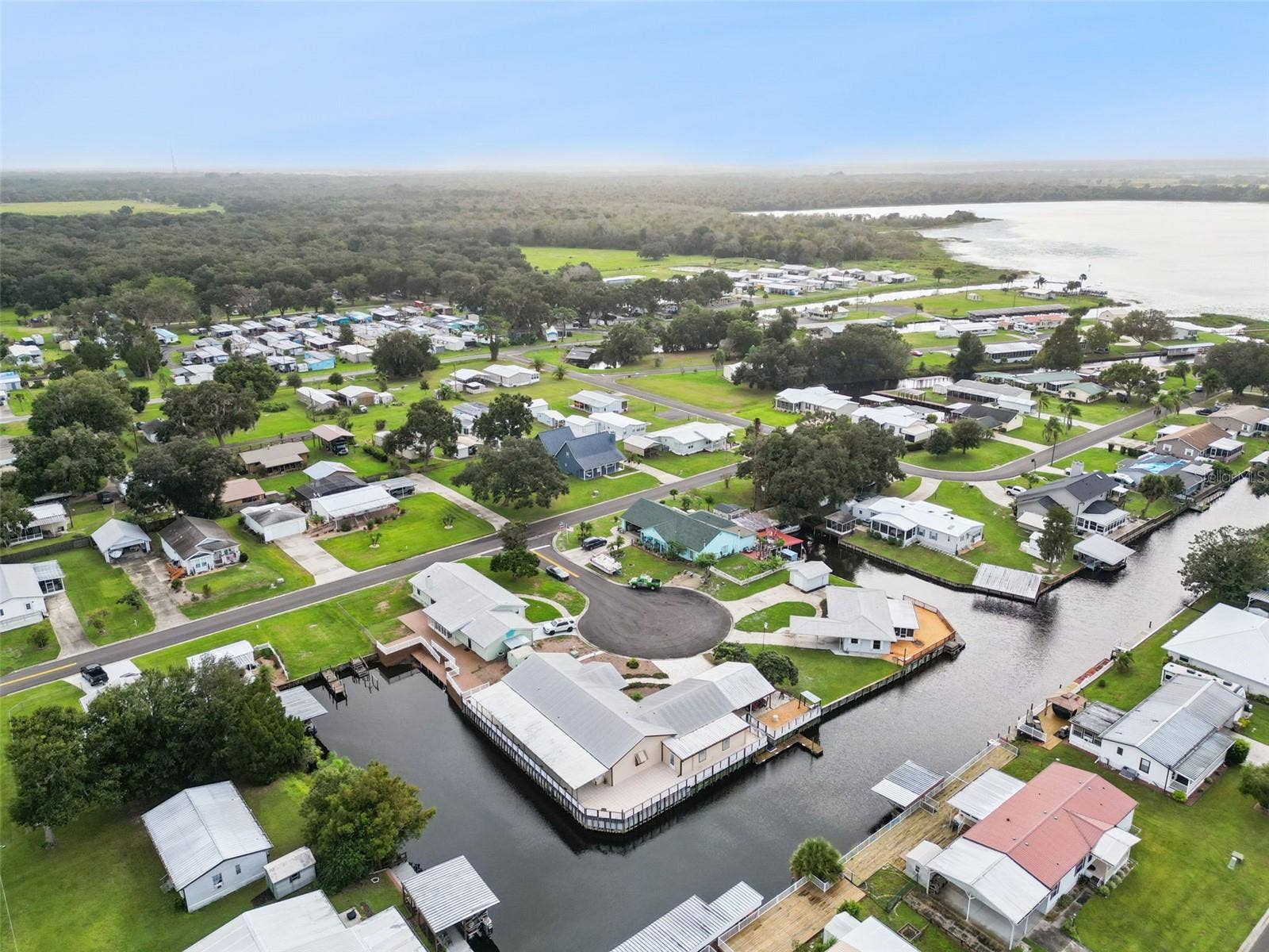 Community Aerial Overview: Elevated drone shot showing the property situated within the quiet, tree-lined waterfront neighborhood.
