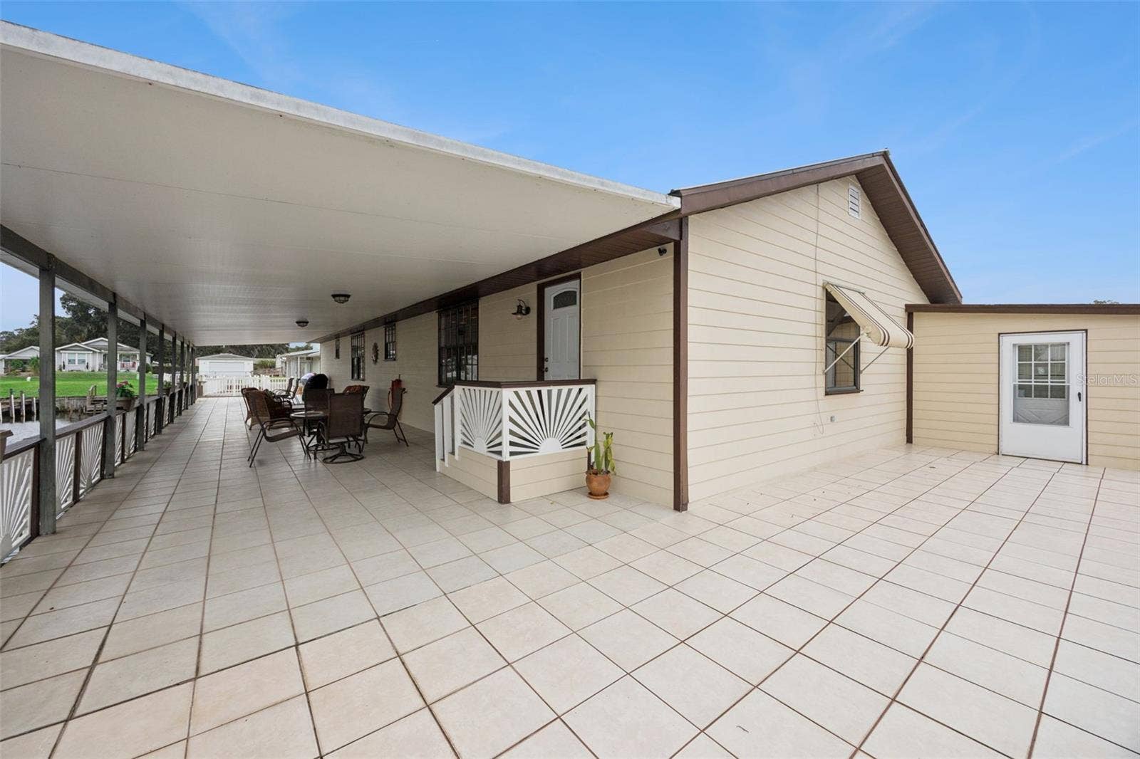 Rear Patio & Exterior Entry: Broad view of the expansive tiled outdoor patio extending along the rear exterior of the home.