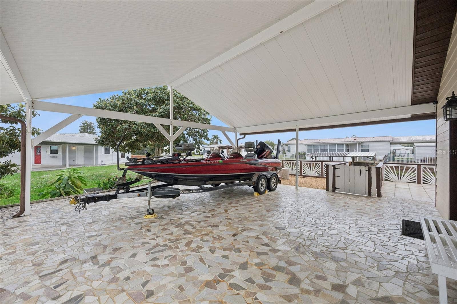 Covered Carport & Boat Parking: Wide covered carport area featuring custom mosaic stone-look flooring, ideally suited for trailered boat or vehicle storage.