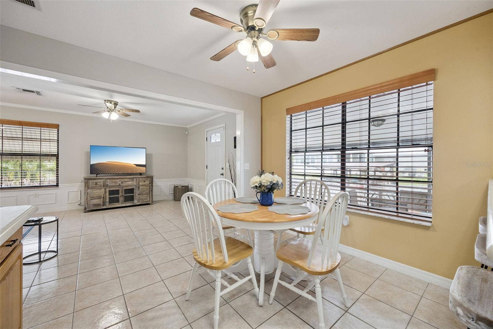 Casual Breakfast Nook: Sunny dinette area directly off the kitchen featuring tile flooring, ceiling fan, and large picture window with wooden blinds.