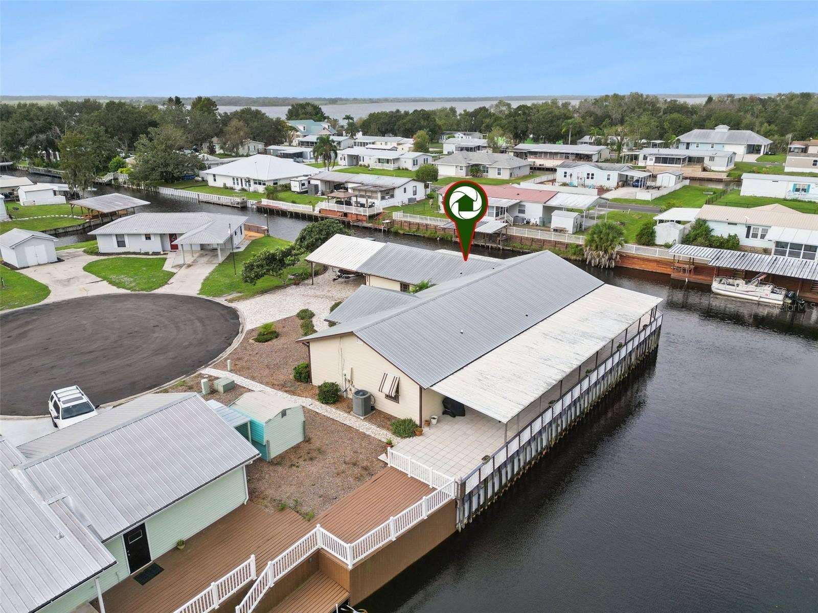 Aerial Rear Deck Pin: Aerial photo of the home's rear exterior and patio deck featuring a property location pin.