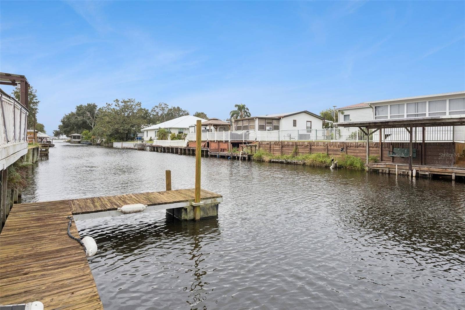 Wooden Boat Dock: Sturdy wooden boat dock with mooring posts providing direct water access for boating and fishing