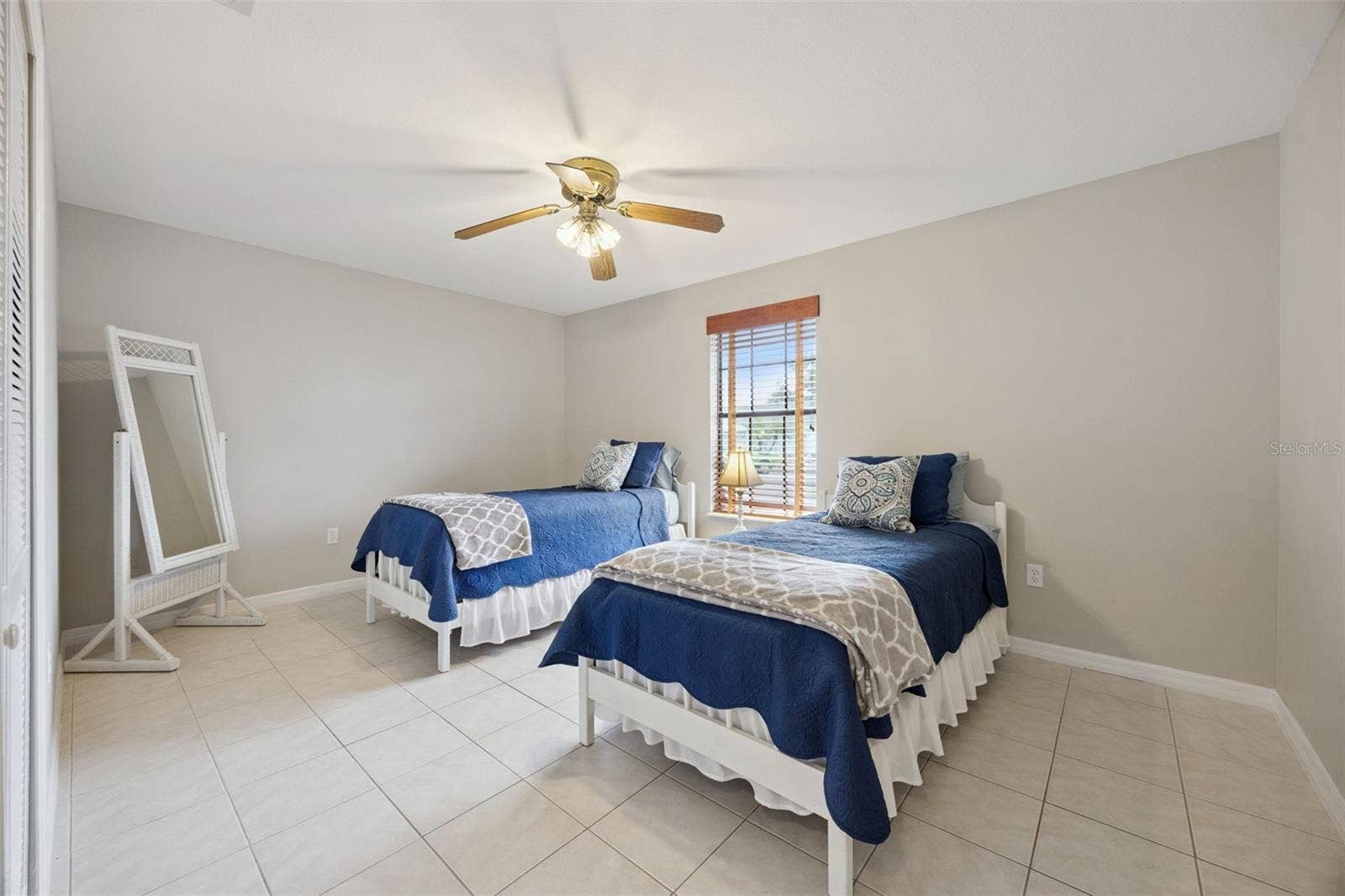 Twin Bedroom Alternate Angle: Bright secondary bedroom showcasing easy-care tile floors, ceiling fan, and window offering pleasant natural light.