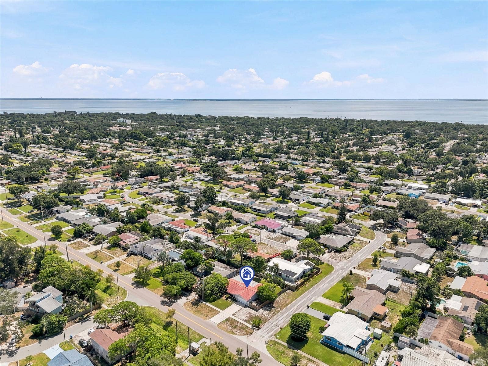 1890 62ND AVENUE S, St Petersburg, FL 33712 An elevated view highlights the homes corner lot and tree-filled surroundings, with the bay forming a scenic backdrop beyond the neighborhood.