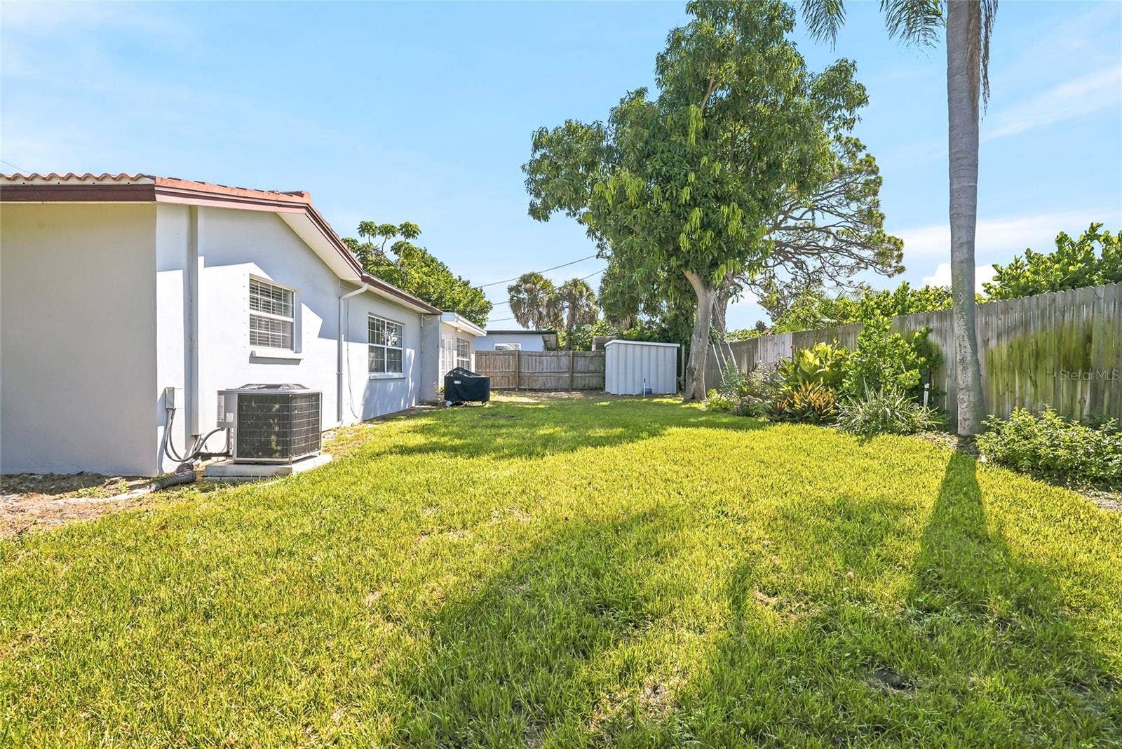 1890 62ND AVENUE S, St Petersburg, FL 33712 Stretch out in the sunshine or settle beneath the trees, with open lawn, established planting beds, and wood fencing framing the backyard.