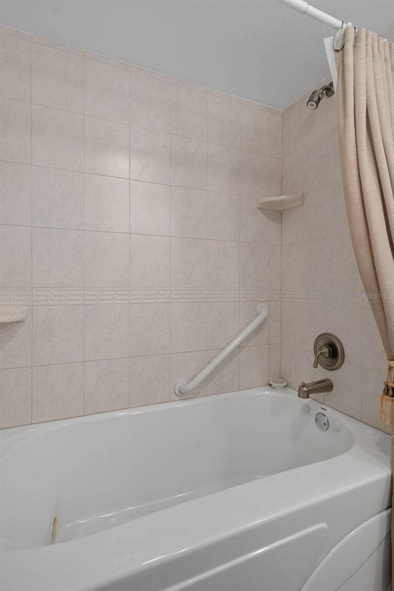 1230 GULF BOULEVARD, #303, Clearwater Beach, FL 33767 Jetted tub/shower combo in primary suite. A small storage area is just behind.