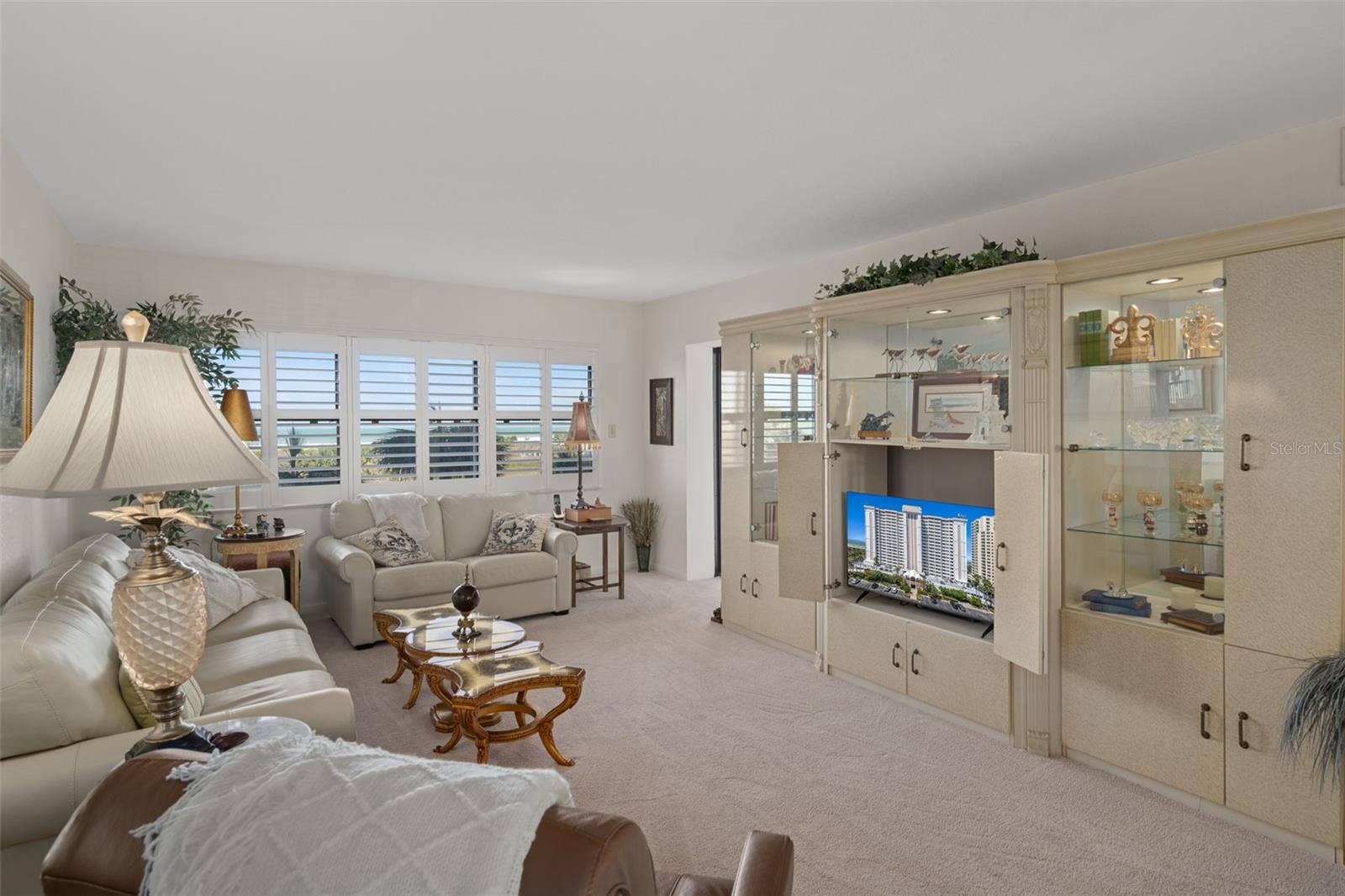 1230 GULF BOULEVARD, #303, Clearwater Beach, FL 33767 Living Room features windows with plantation shutters across the back as well as access to the patio through a sliding door.