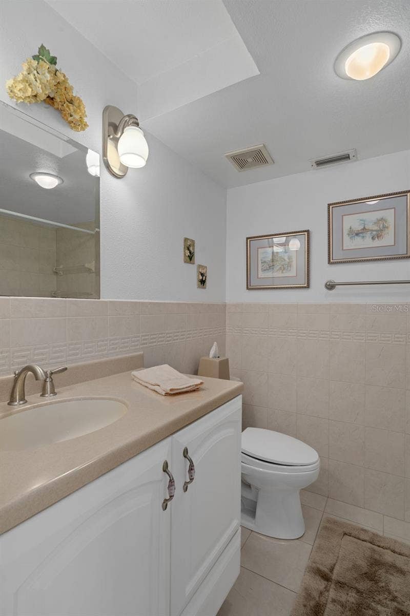 1230 GULF BOULEVARD, #303, Clearwater Beach, FL 33767 En-suite bath features single vanity with Corian countertop and a storage cabinet + drawer