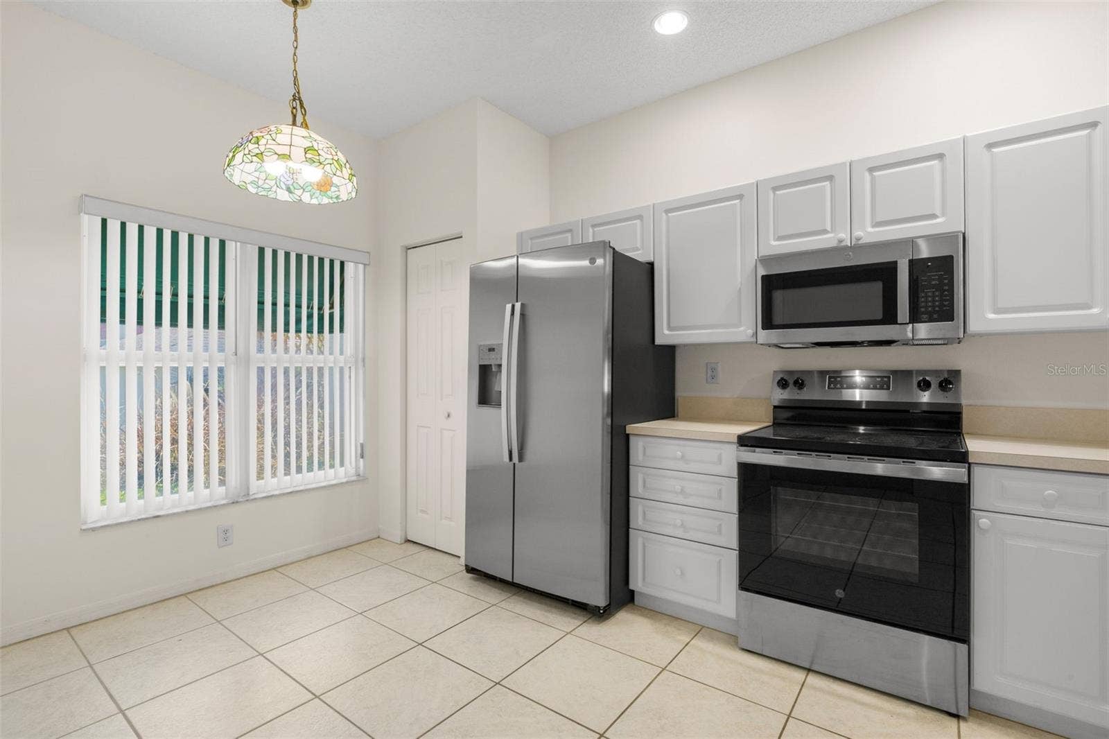 Spacious eat-in kitchen featuring ample cabinetry, generous counter space, and a dedicated dining area beneath a decorative pendant light.