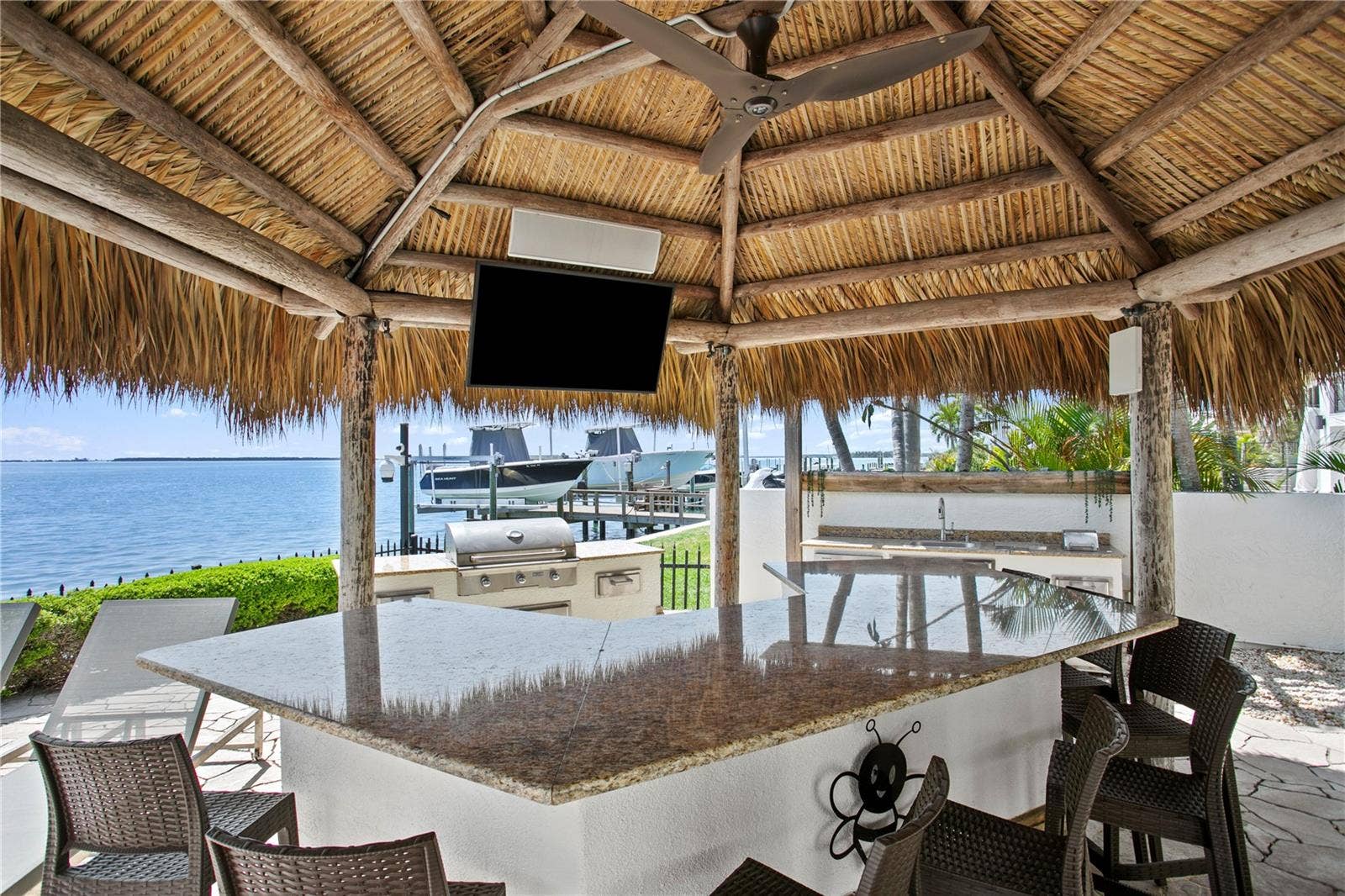 Outdoor kitchen with bar, tiki hut and TV.