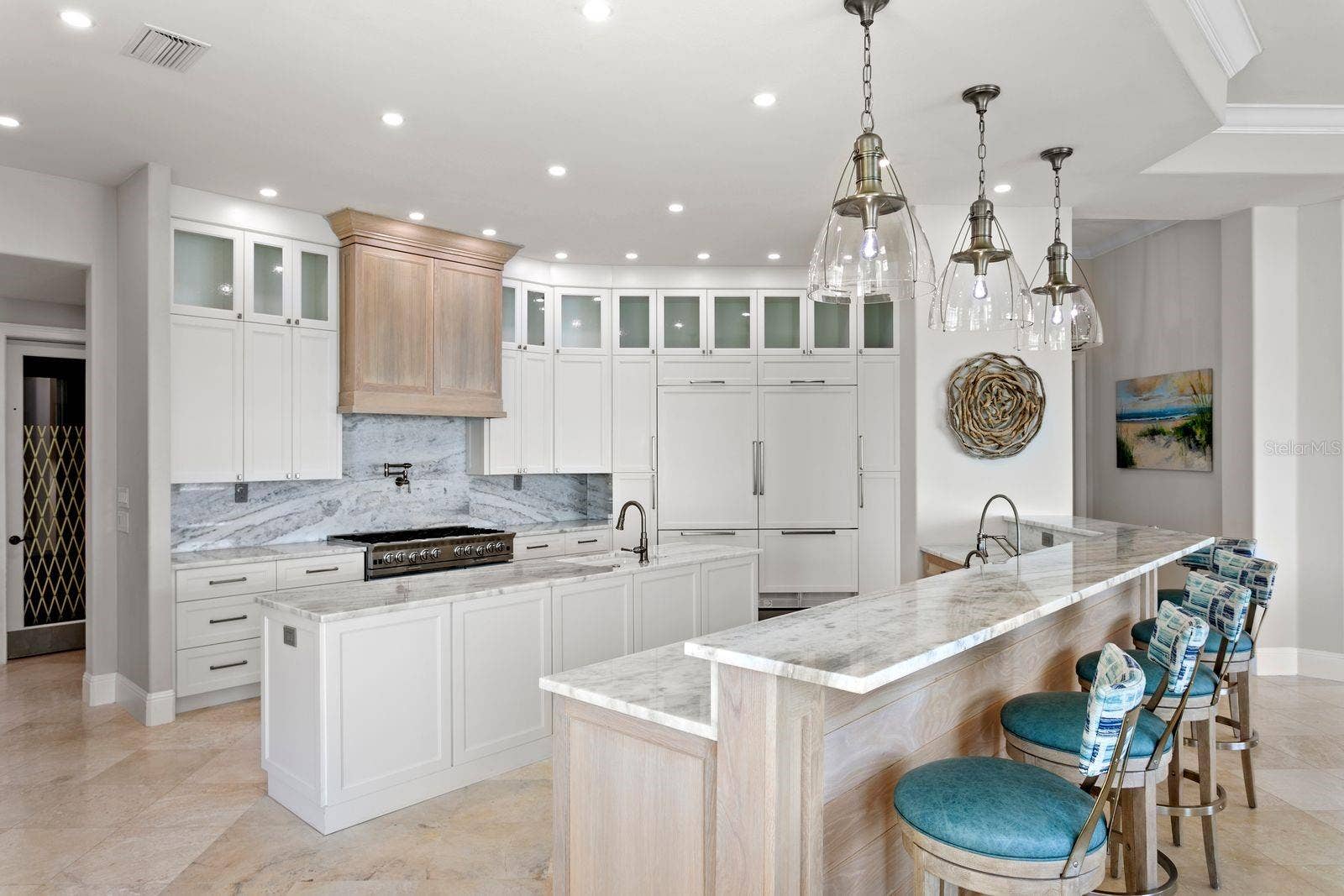 An elegant chef's kitchen appointed with quartz surfaces and statement designer lighting.