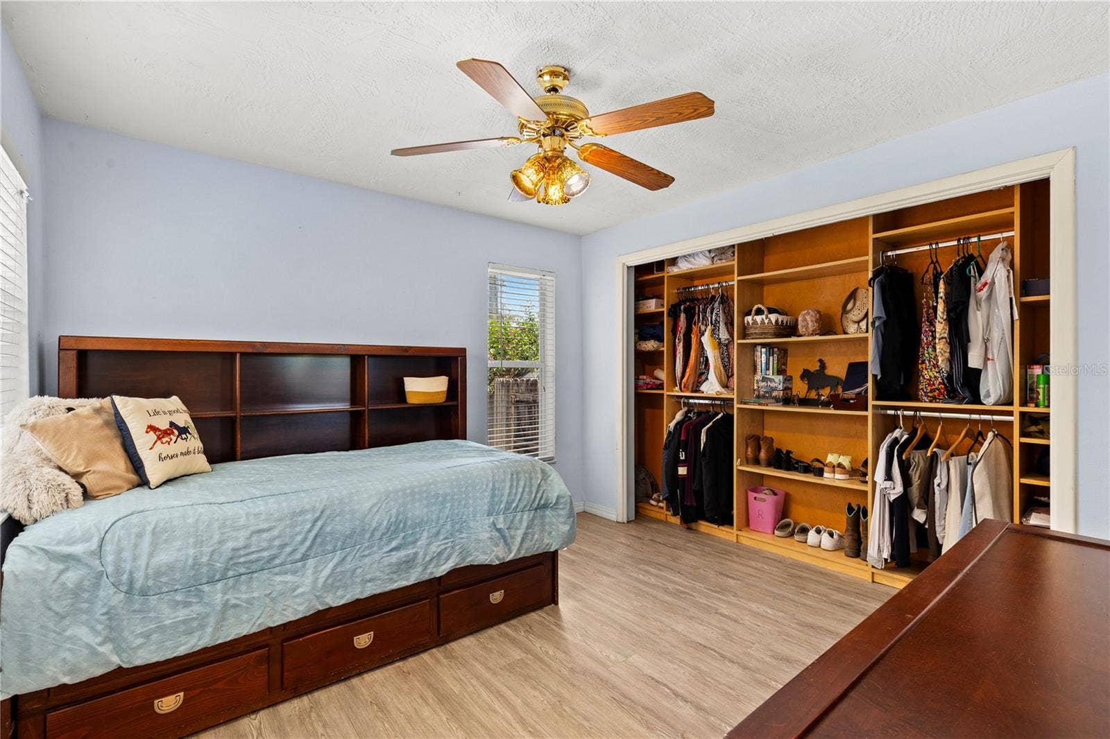 Well-appointed second bedroom featuring abundant natural light and a custom closet organizer designed to maximize storage and keep everything neatly arranged.