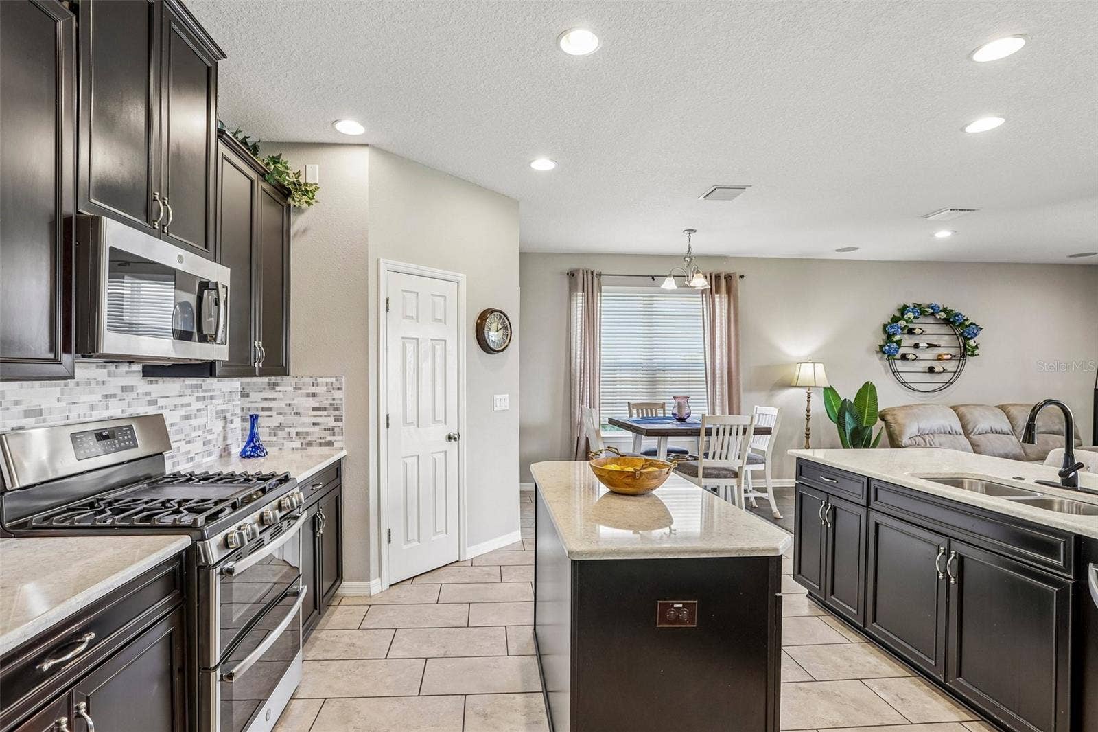 17628 BRIGHT WHEAT DRIVE, Lithia, FL 33547 Kitchen area with 42" cabinets, stained appliances, gas range, beautiful backsplash, Island and quartz