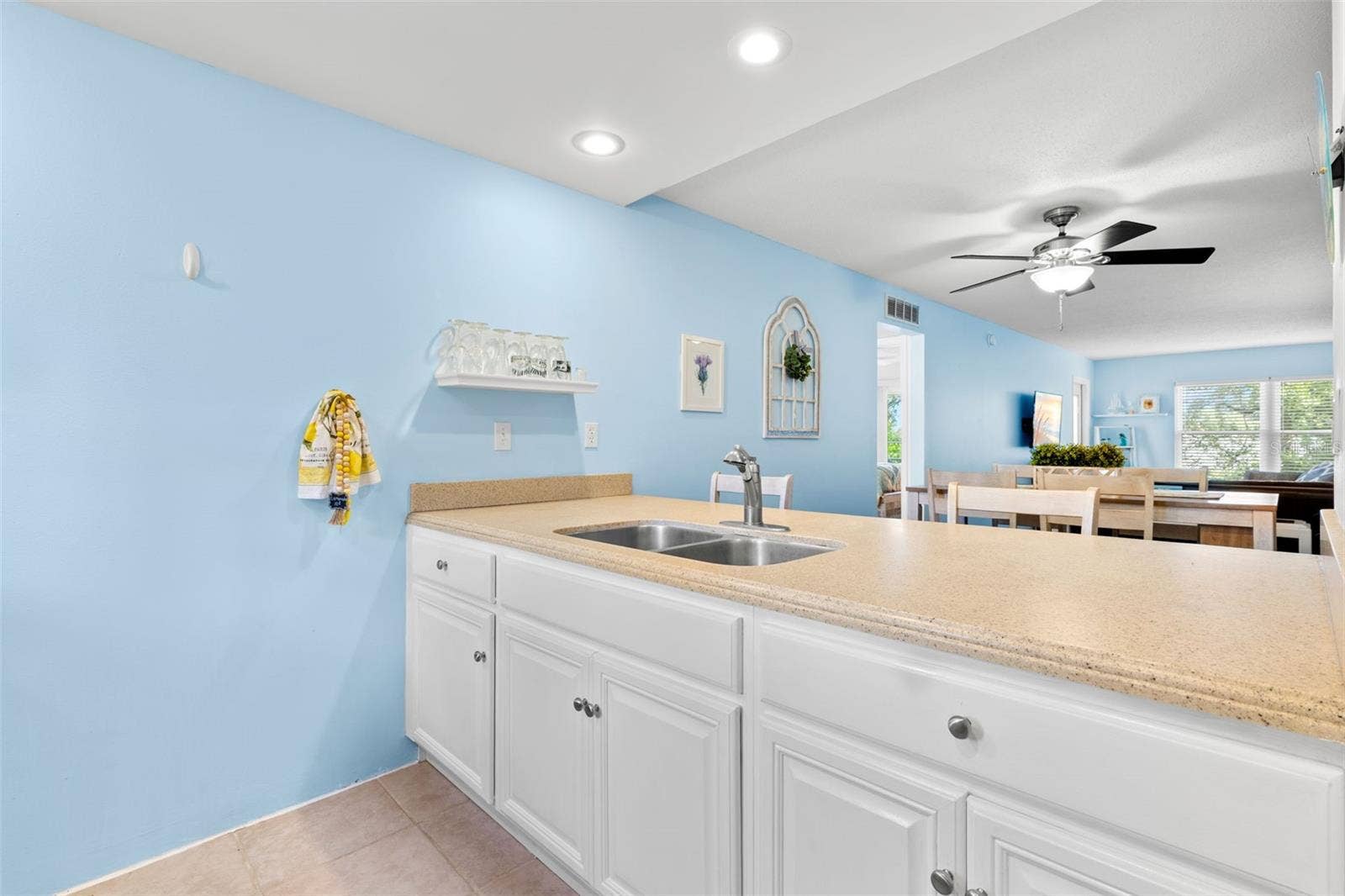 12760 INDIAN ROCKS ROAD, #107, Largo, FL 33774 A long Corian breakfast bar extends the kitchen toward the dining and living areas, pairing generous counter space with a double-basin sink while keeping the room visually connected to the main living space.