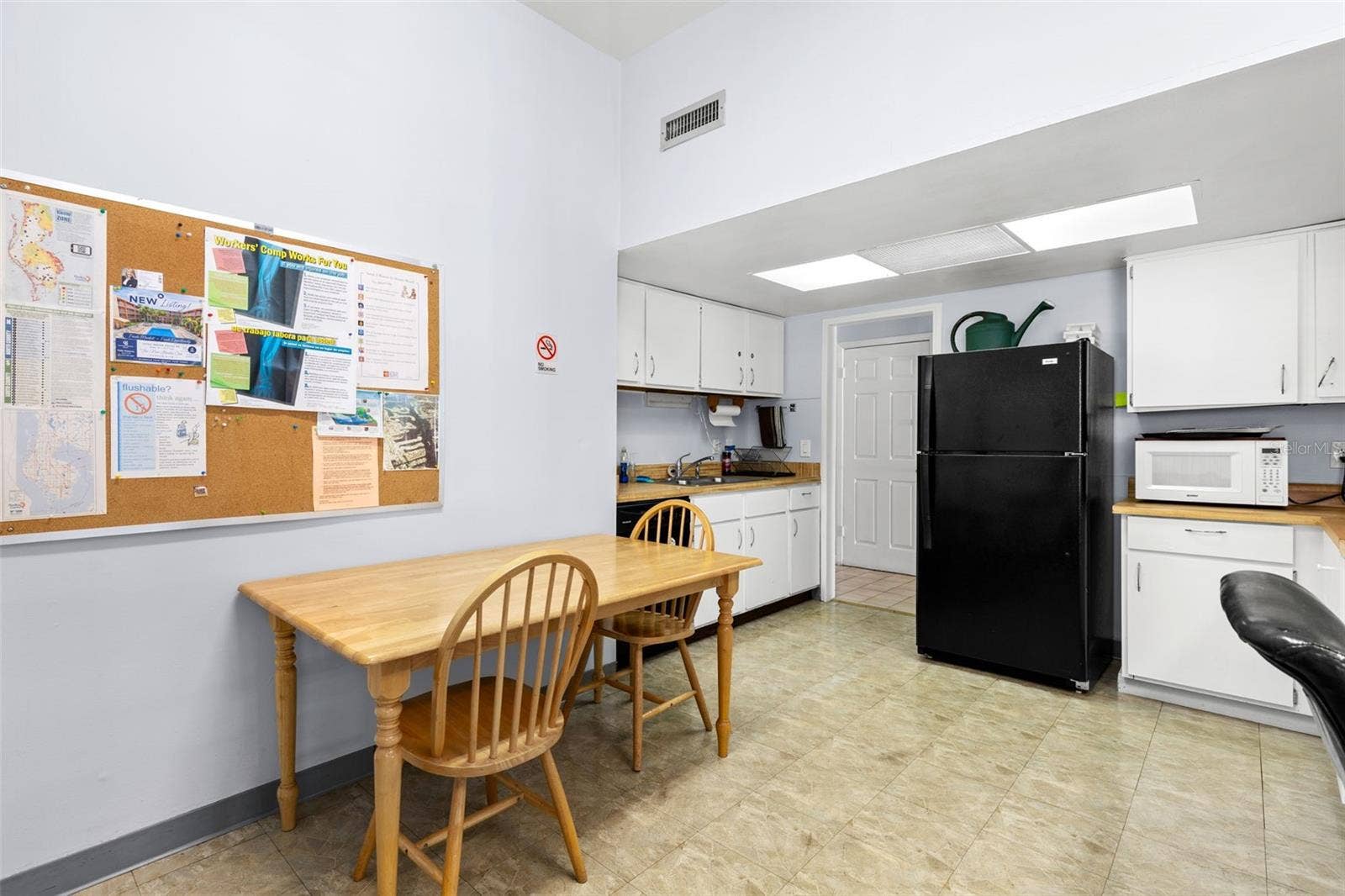 12760 INDIAN ROCKS ROAD, #107, Largo, FL 33774 The clubhouse includes a community kitchen with full-size refrigerator, microwave, sink, cabinetry and table seating, providing space for gatherings and shared activities.