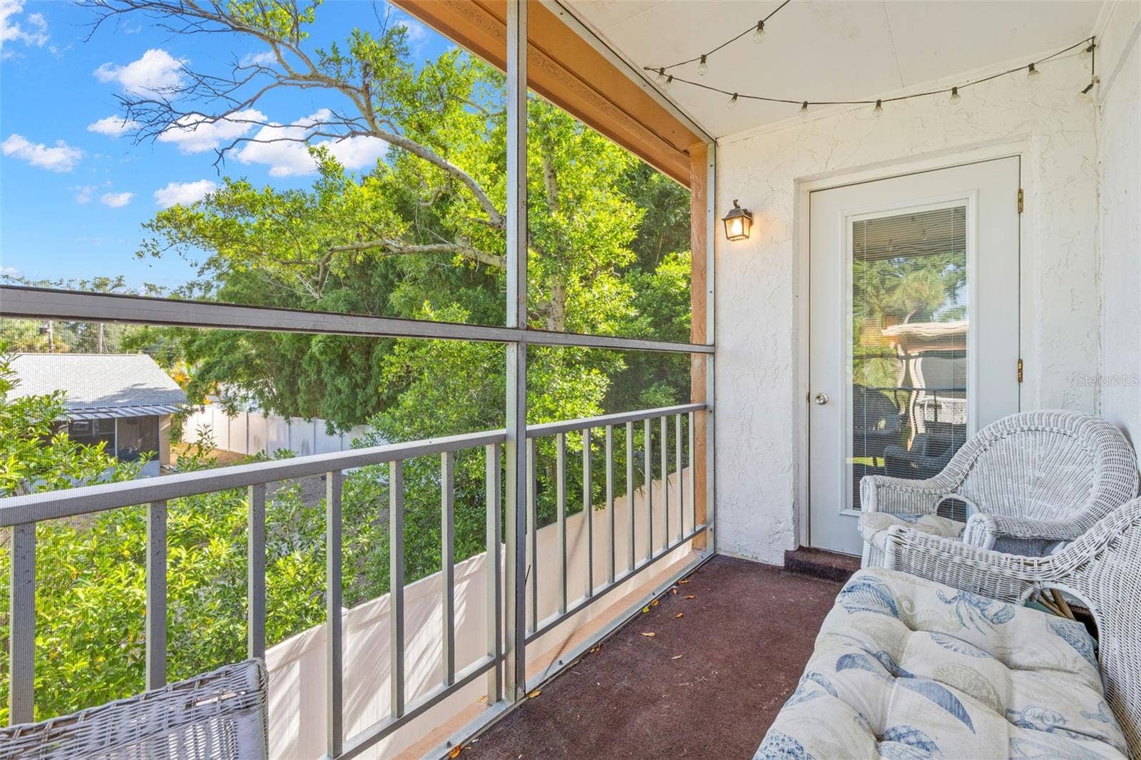 12760 INDIAN ROCKS ROAD, #107, Largo, FL 33774 Positioned between the living room and primary bedroom, the screened balcony creates a comfortable outdoor extension of both spaces, with room for seating and a leafy view framed by mature trees.