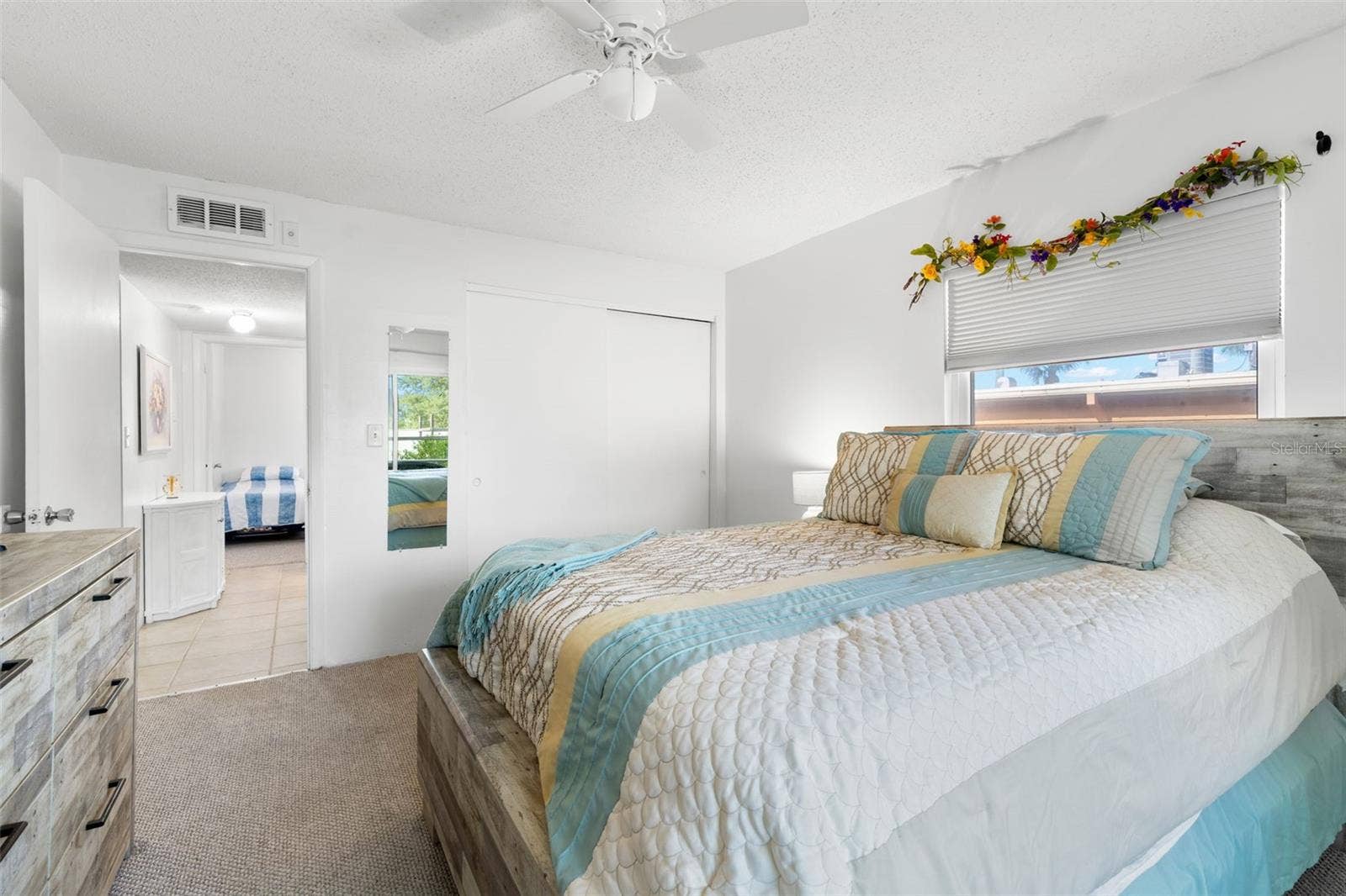 12760 INDIAN ROCKS ROAD, #107, Largo, FL 33774 A built-in closet with sliding doors provides storage in the primary bedroom, while neutral carpet, a ceiling fan and a window complete the space.